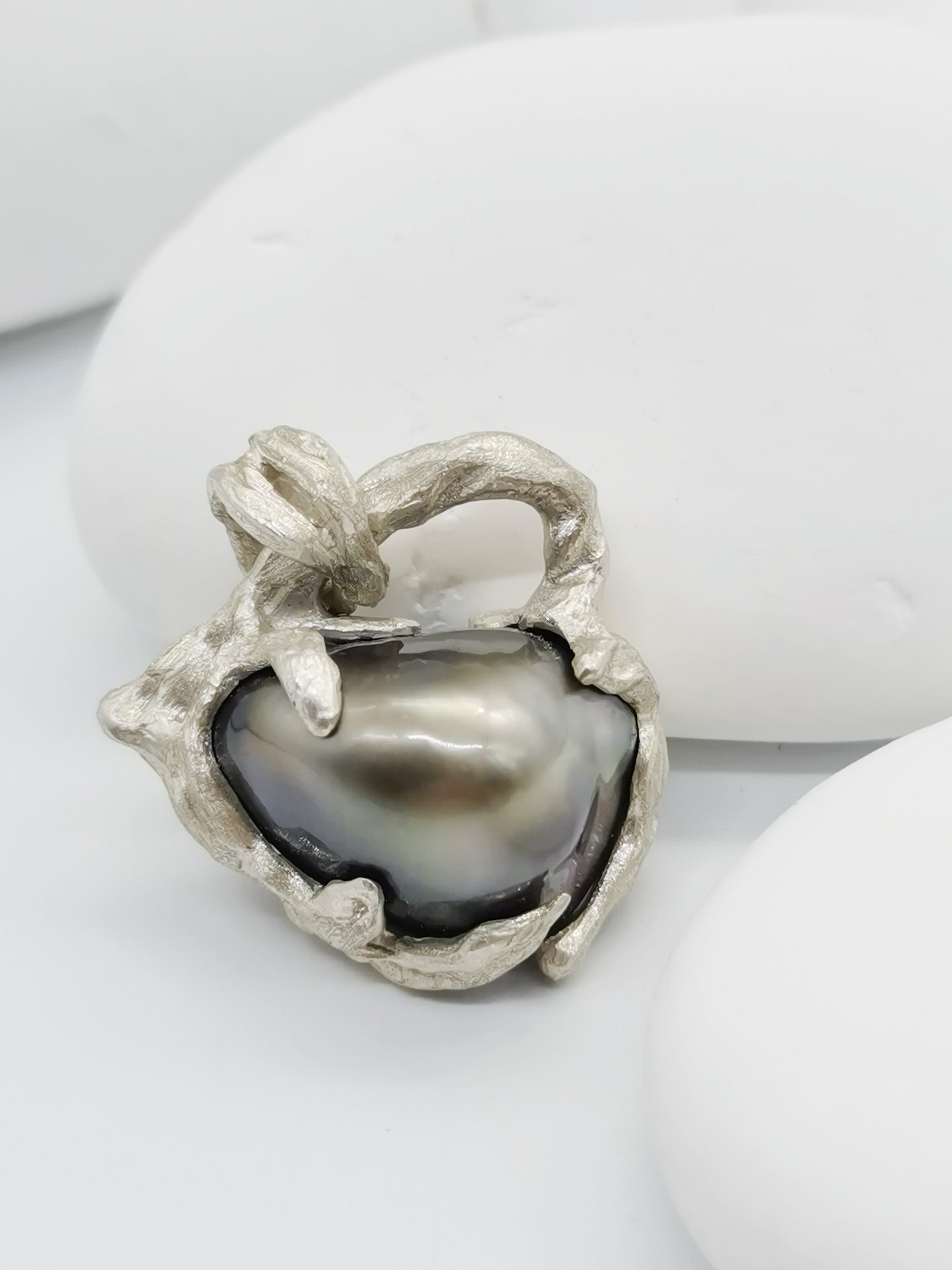 Close-up image of the heart pendent showing off the unique iridescent colour of the lustre of the baroque pearl 