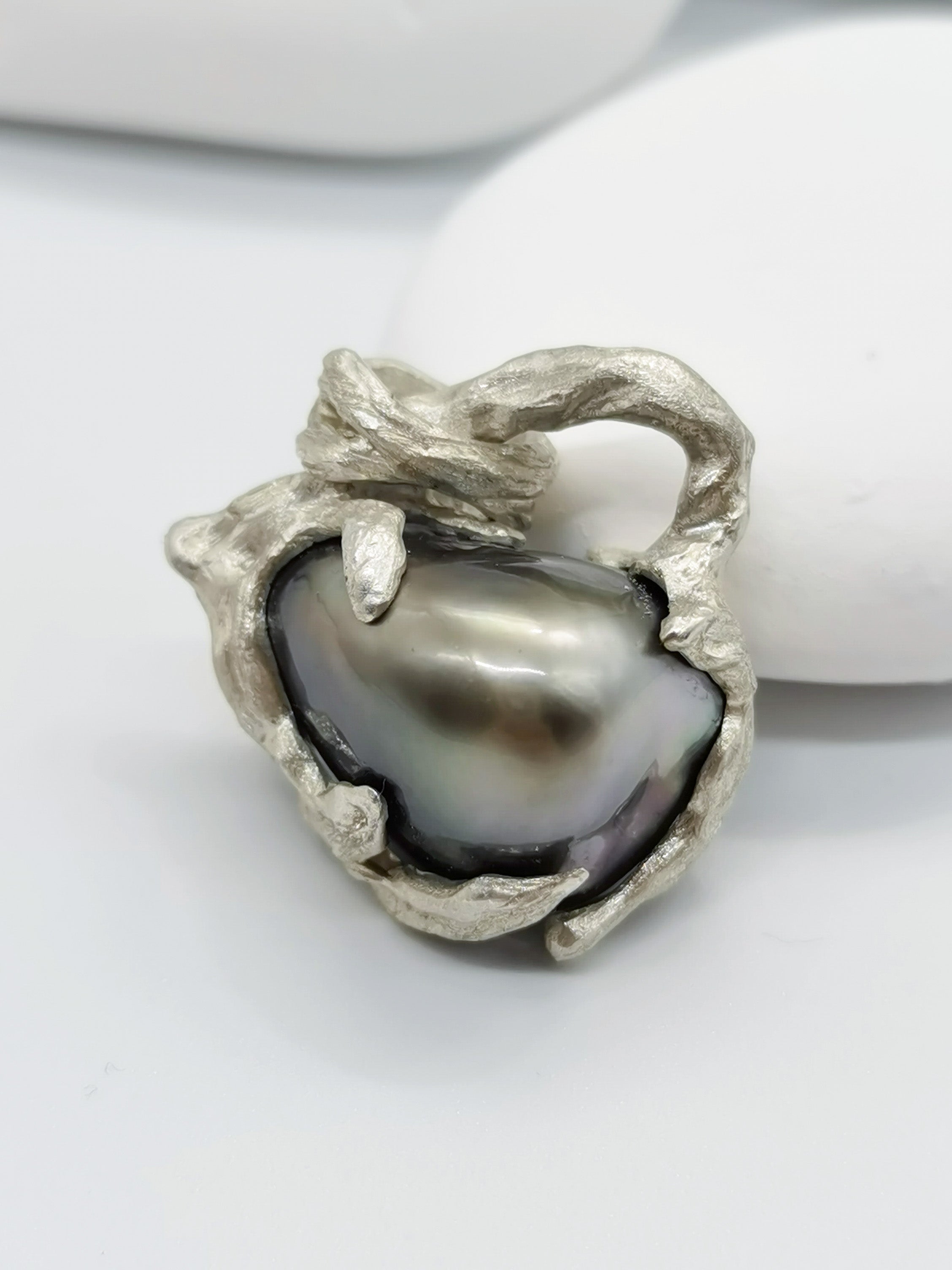 Details of the Tahitian pearl heart pendant's intricate silver work and high lustre of the pearl giving out high reflection