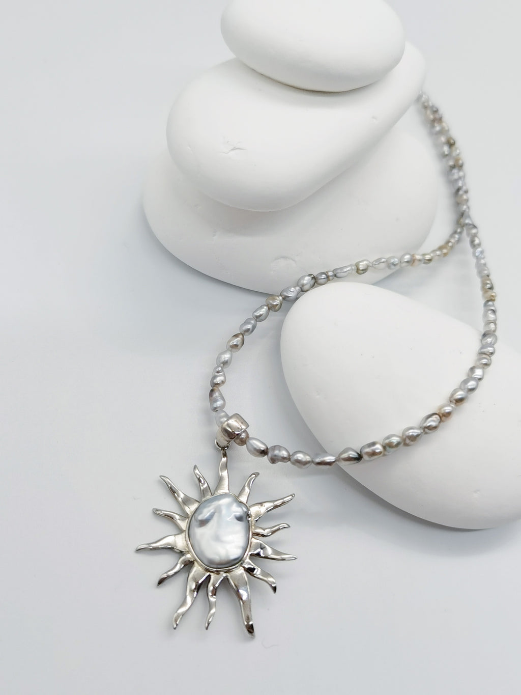 CLOSE UP VIEW OF BAROQUE SUNBURST PENDANT ALONE against white background, from a slight different angle to show the subtle blue overtone of the pearl. The pendant is paired with a necklace as production offering.