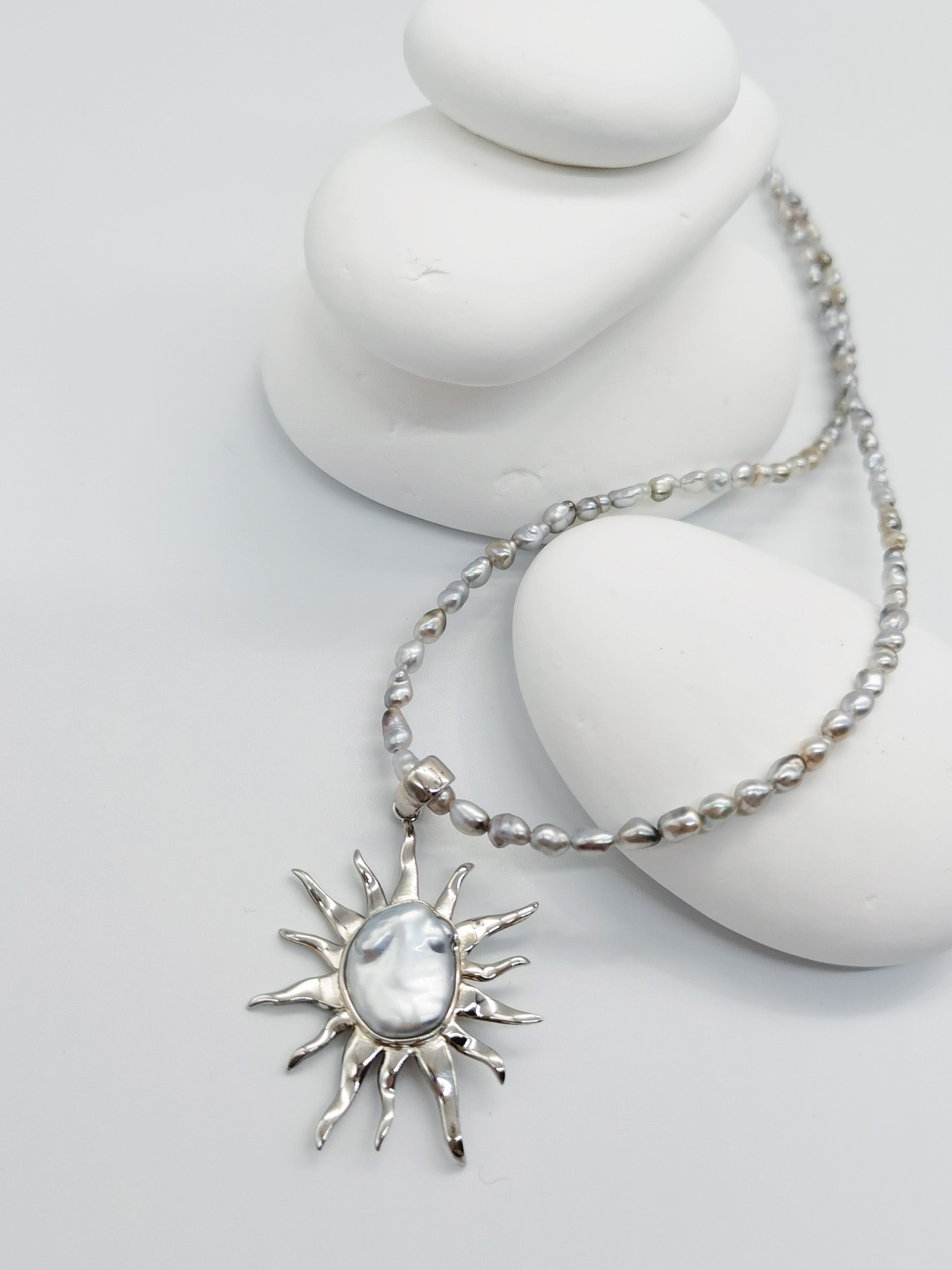 CLOSE UP VIEW OF BAROQUE SUNBURST PENDANT ALONE against white background, from a slight different angle to show the subtle blue overtone of the pearl. The pendant is paired with a necklace as production offering.