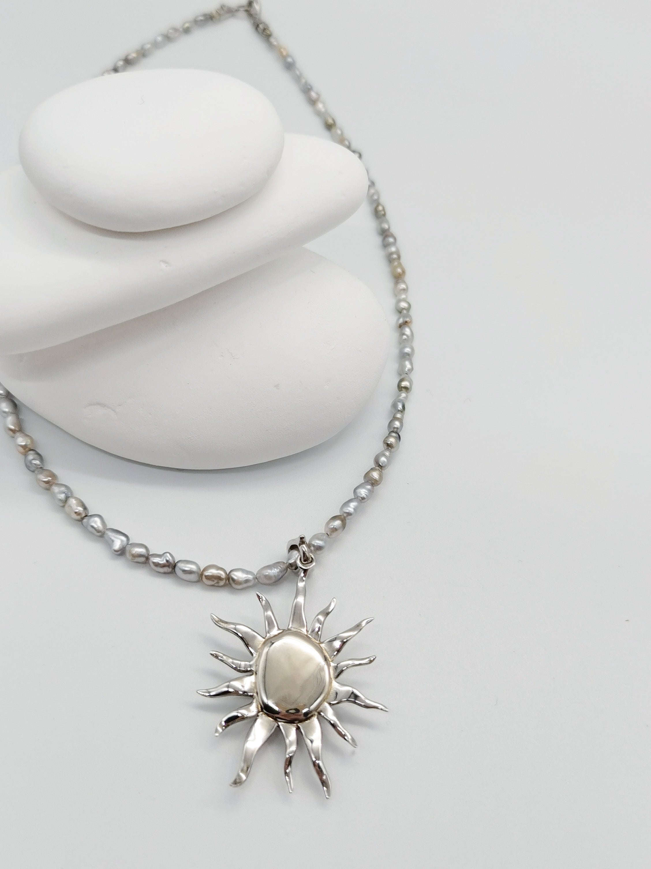 Details of the close back mounting of the white baroque pearl pendant, paired with a Tahitian keshi pearl necklace, lay flat on white background. 