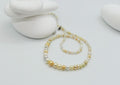 White and cream pearl strand necklace with graduated pearls displayed on white stones, showing the full length and silver clasp detail