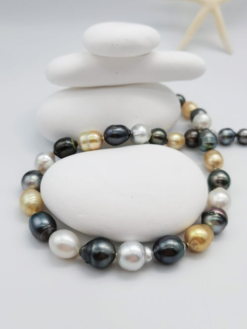 Multicoloured baroque pearl necklace elegantly draped around smooth white stones with starfish accent, highlighting the beautiful mix of pearl colours and organic shapes