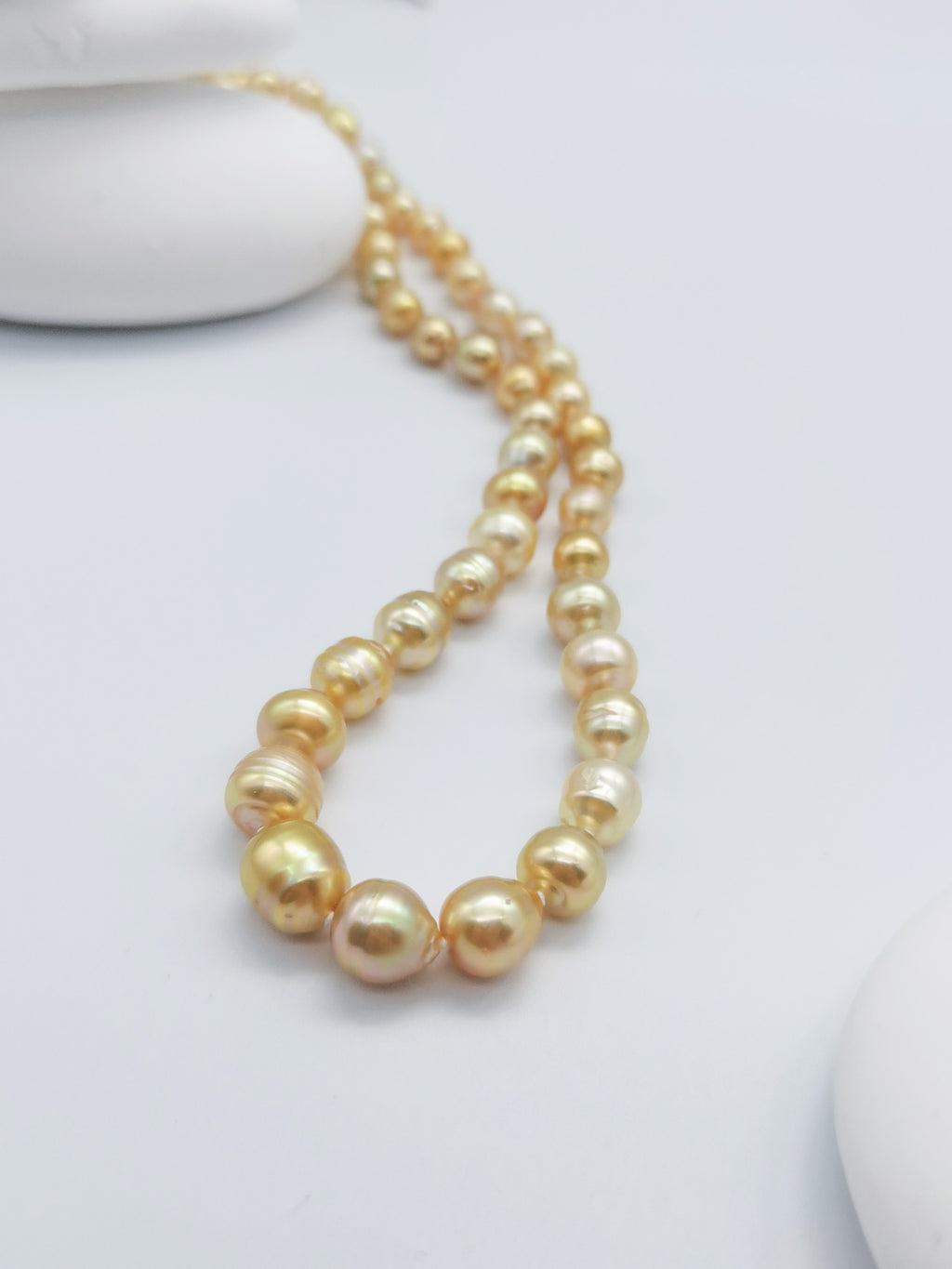 Golden baroque pearl necklace with lustrous graduated pearls in warm golden tones, elegantly displayed on clean white background