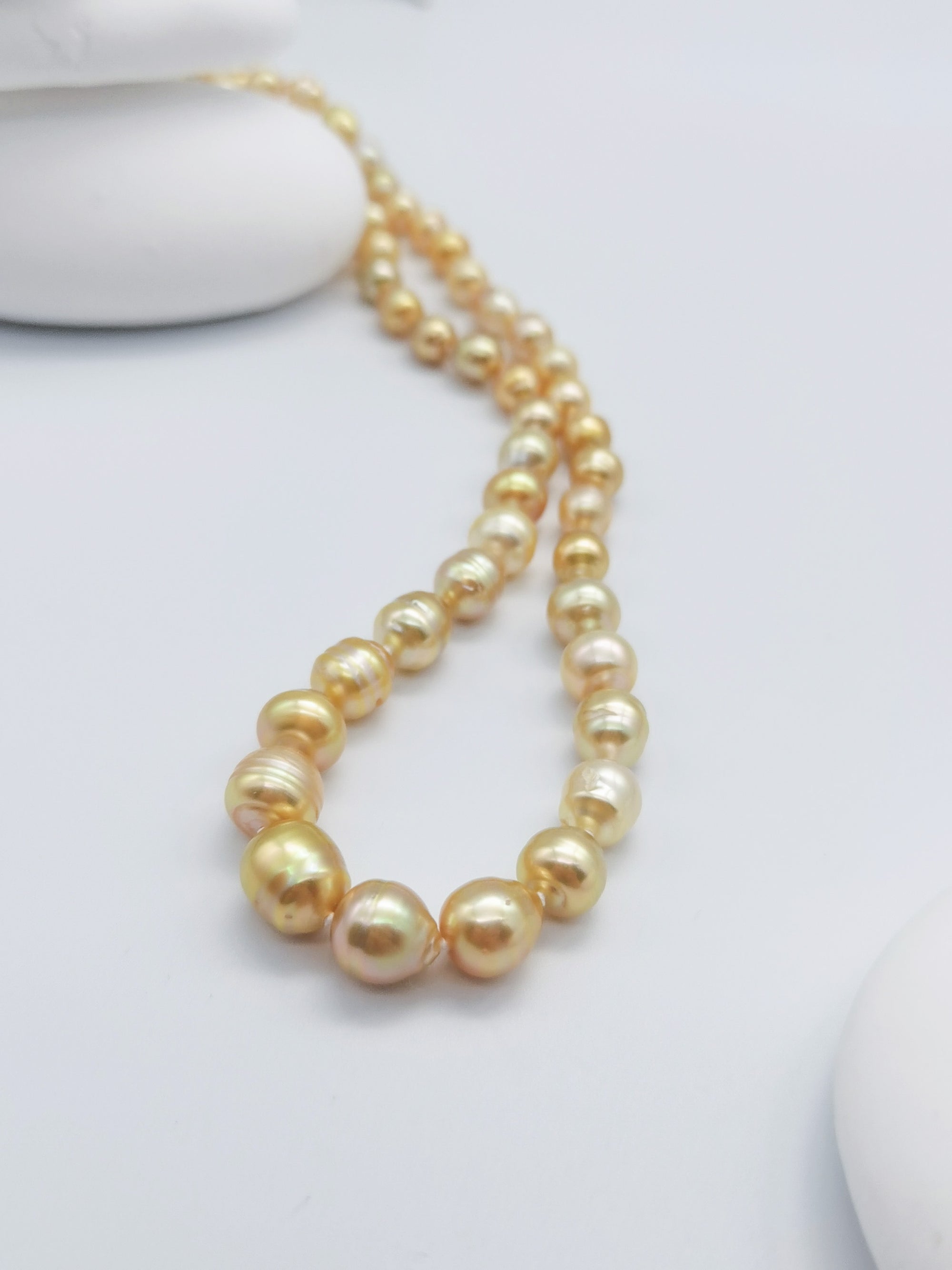 Golden baroque pearl necklace with lustrous graduated pearls in warm golden tones, elegantly displayed on clean white background