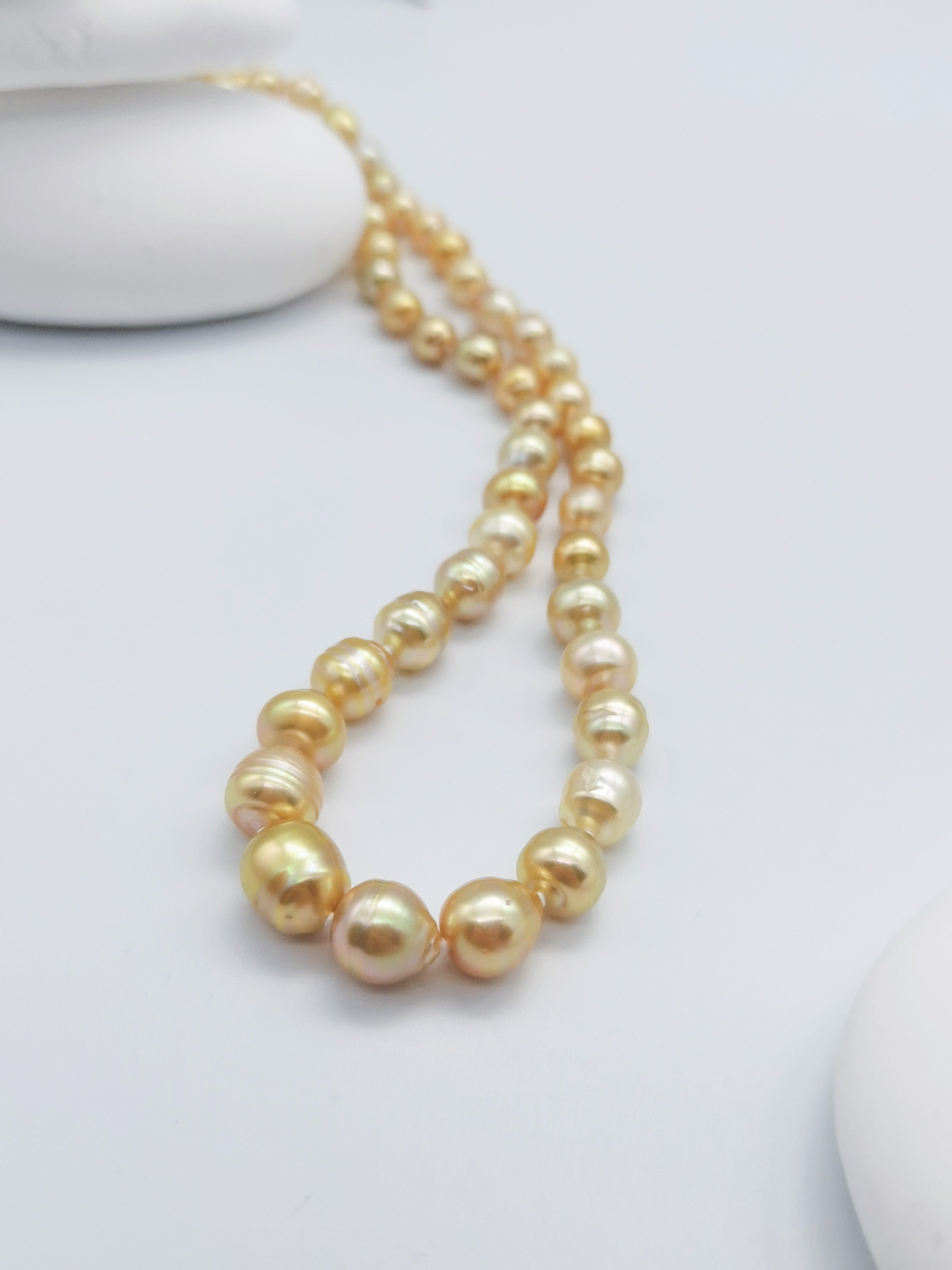 Golden baroque pearl necklace with lustrous graduated pearls in warm golden tones, elegantly displayed on clean white background