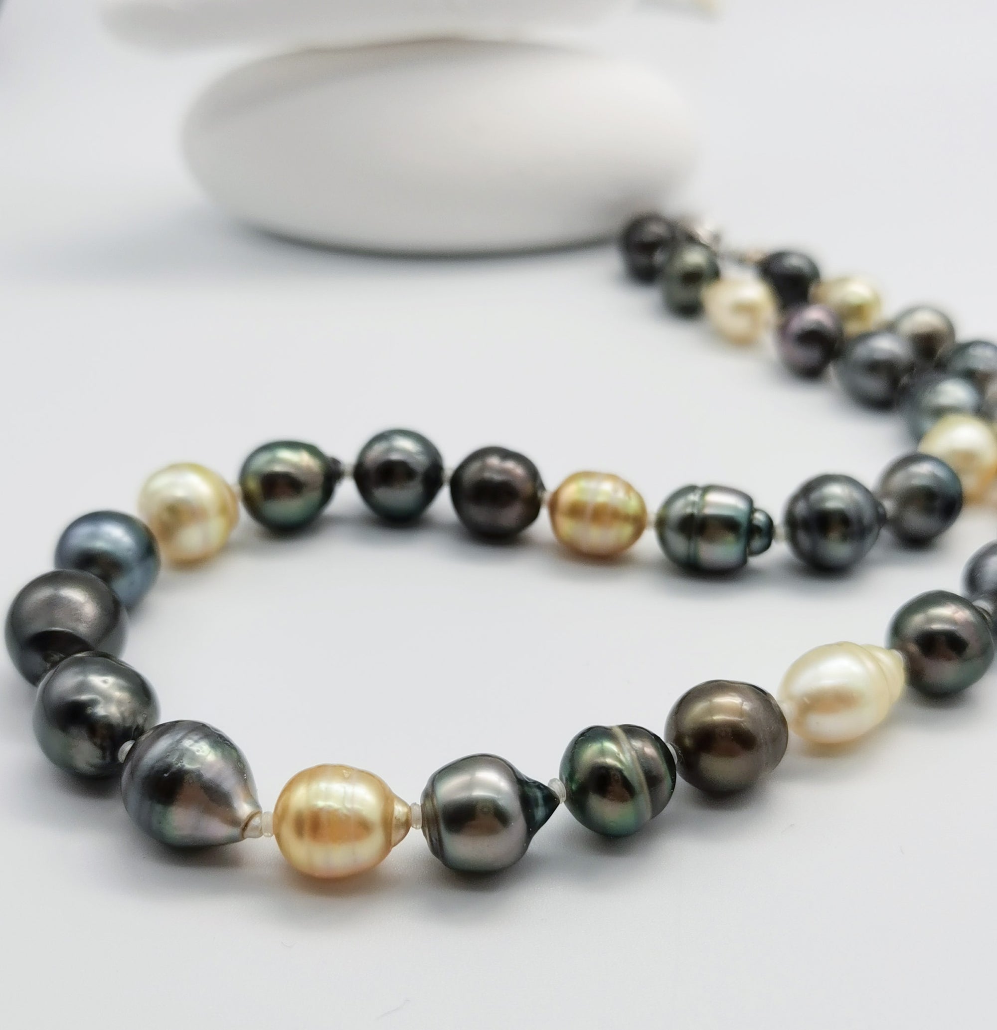 Multicoloured baroque pearl necklace with dark green, black, golden and white pearls in close-up detail, showcasing the lustrous variety of natural pearl colours and shapes