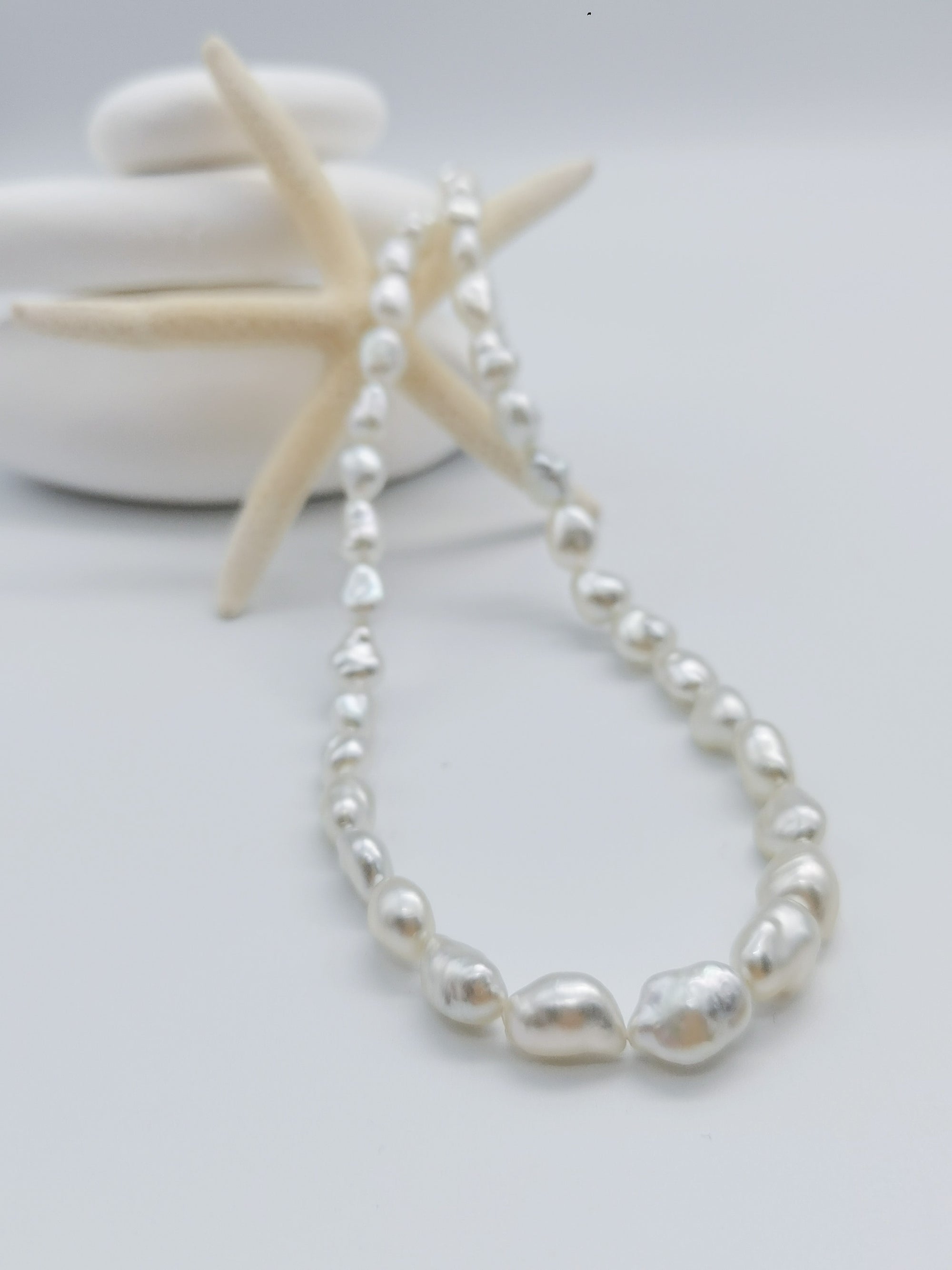 South Sea white keshi pearl strand necklace elegantly styled with starfish and white stones background