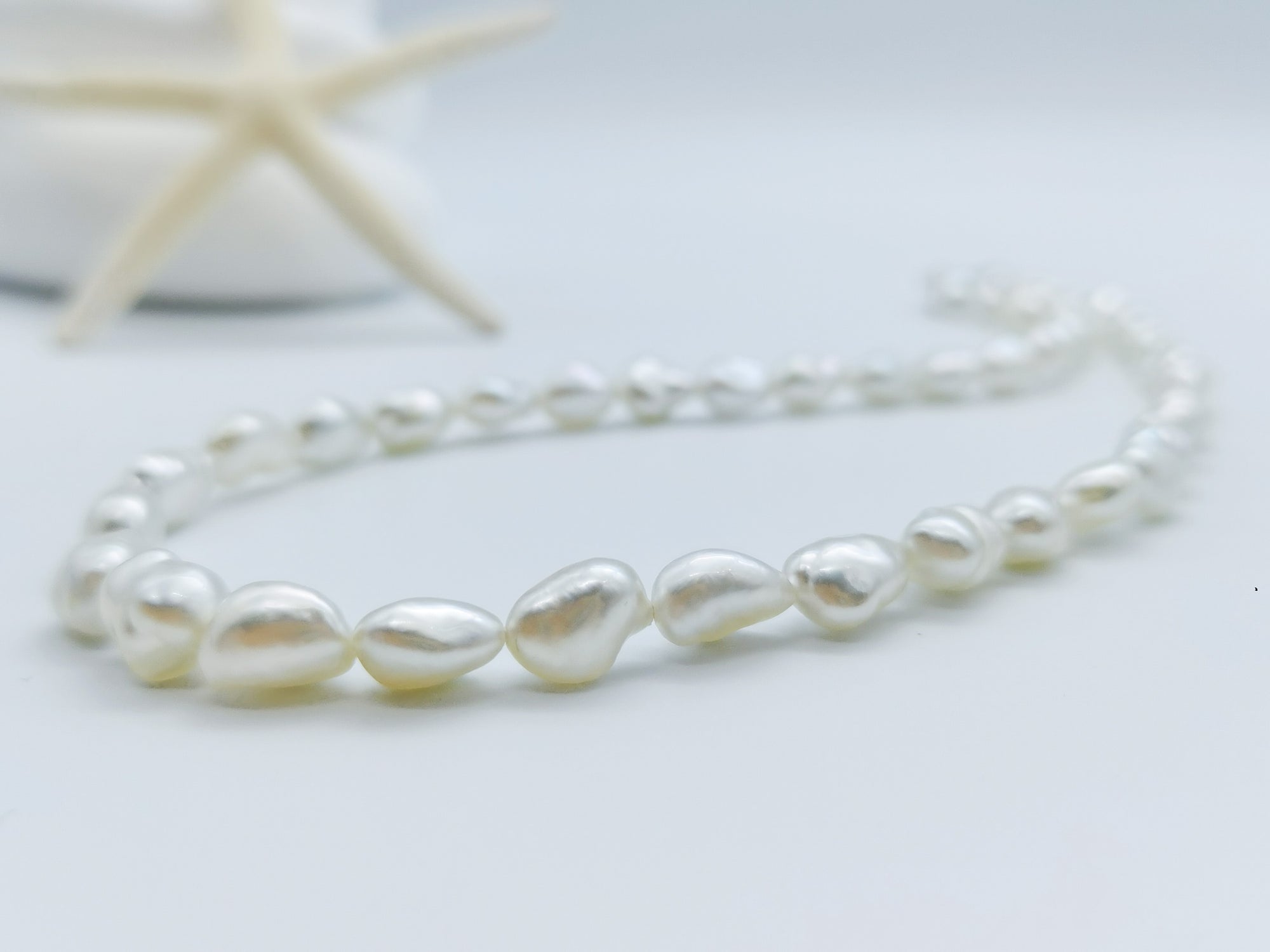 South Sea white keshi pearl strand necklace showing irregular baroque-shaped pearls with natural lustrous finish on white stones background
