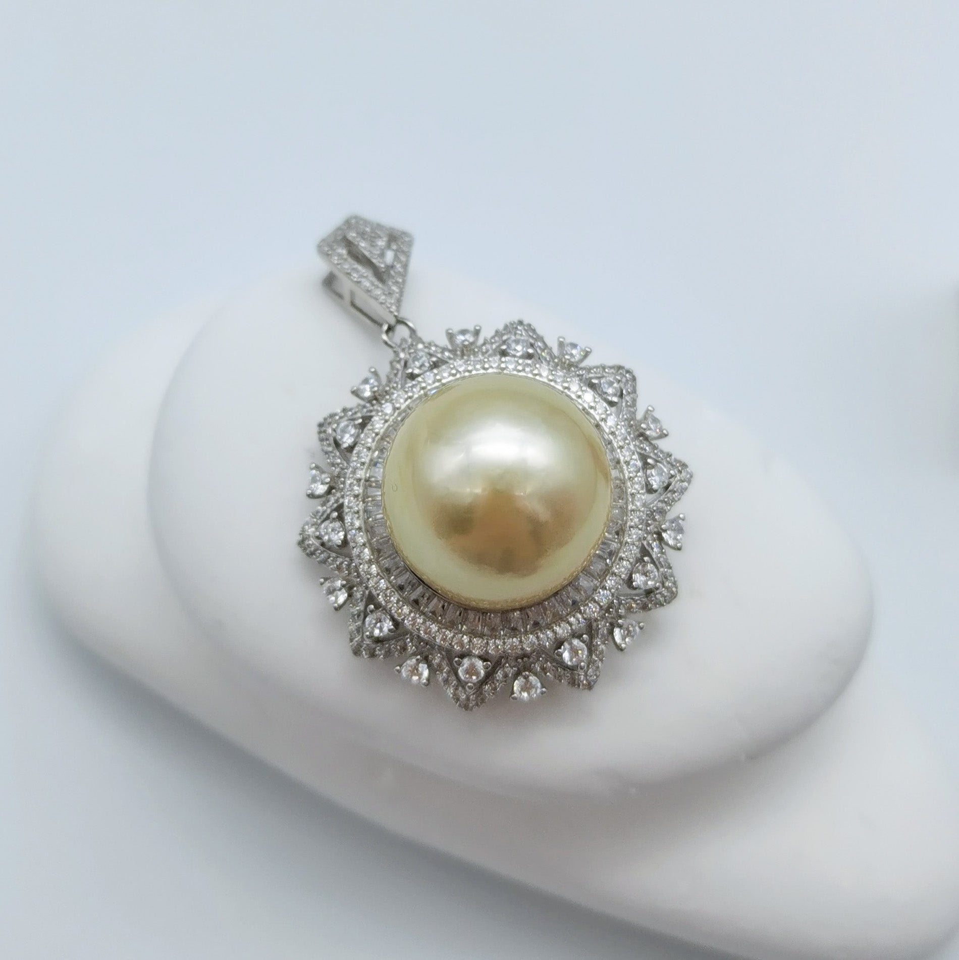Close up Gold South Sea pearl pendant 14.7mm round showing CZ double halo 925 sterling silver compass mount white stone styling