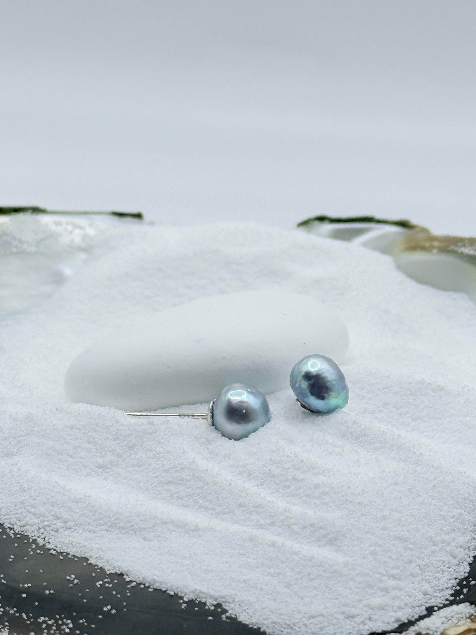Blue Akoya pearl stud earrings showing  lilac silver cyan iridescence on sand and oyster shell styling
