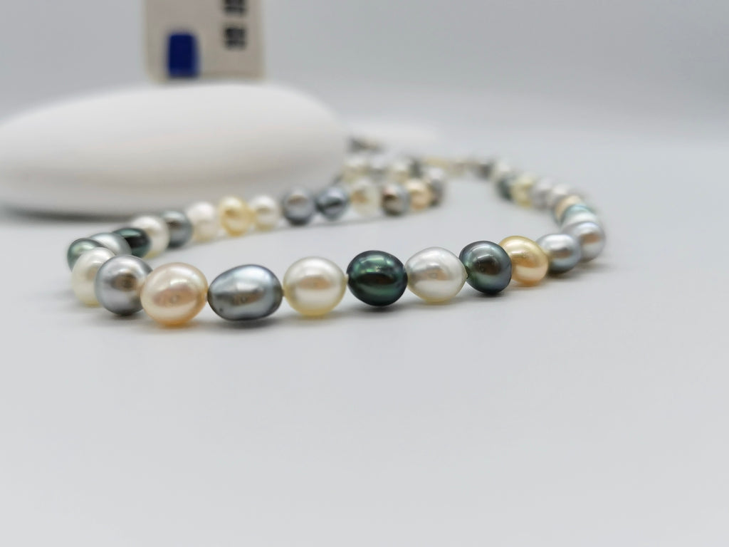 Tri-colour Tahitian and South Sea keshi pearl strand showing natural white, golden and dark pearl colours in flat round shapes