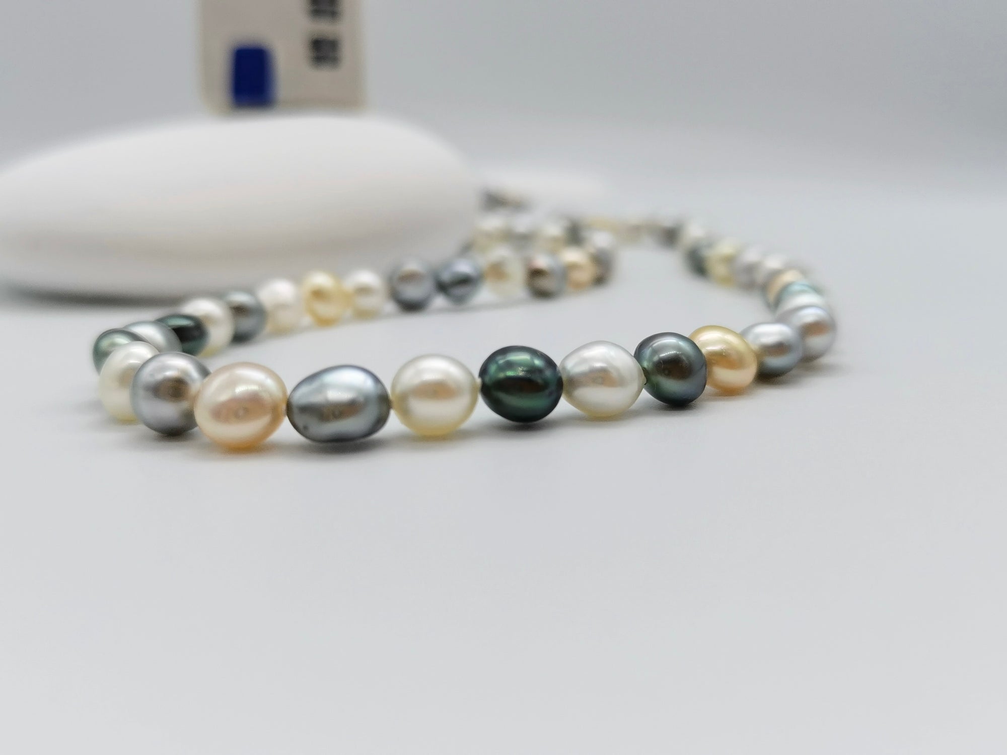 Tri-colour Tahitian and South Sea keshi pearl strand showing natural white, golden and dark pearl colours in flat round shapes