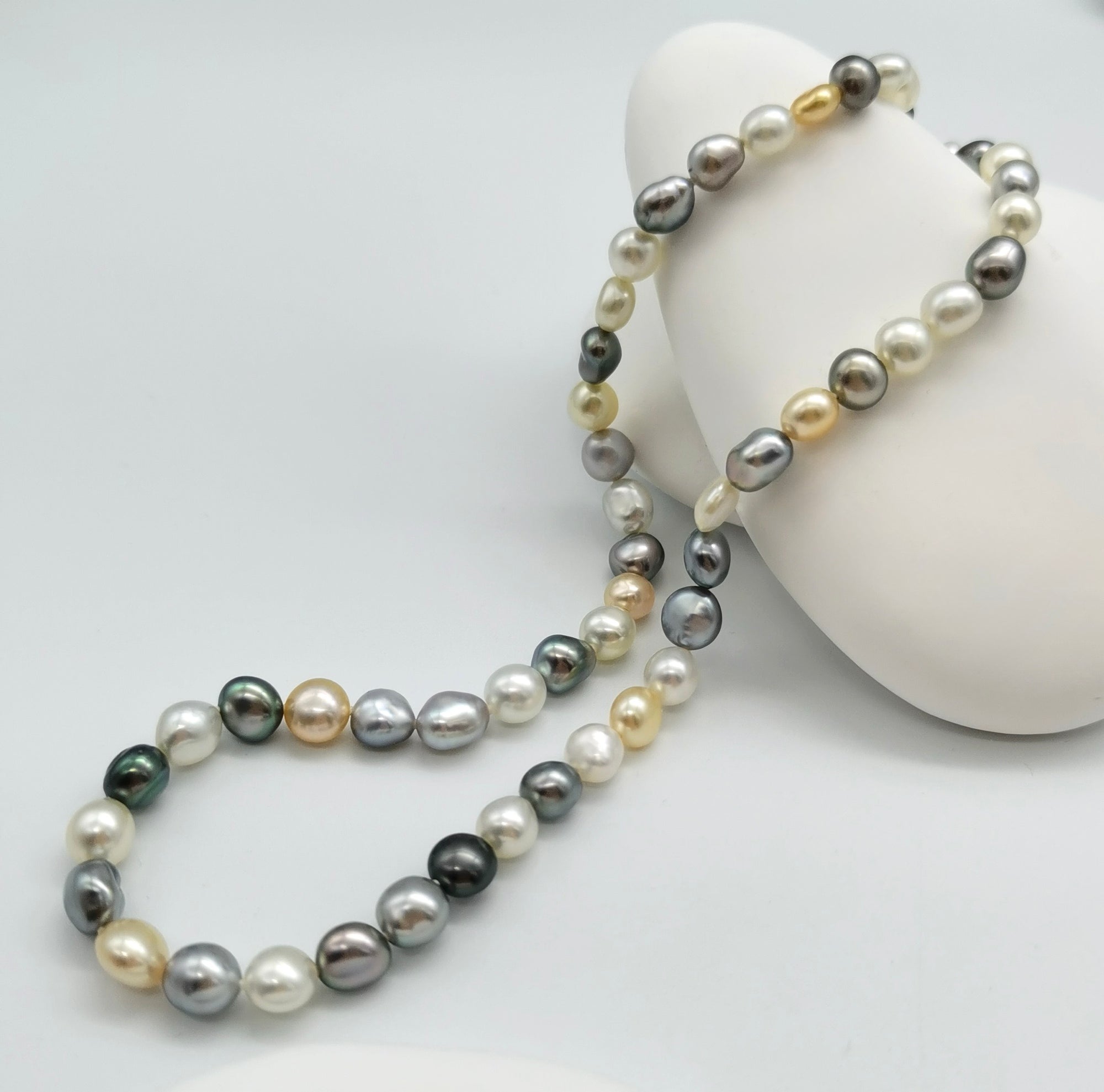 Close-up detail of tri-colour keshi pearl strand showing flat round Tahitian and South Sea pearls in natural colours