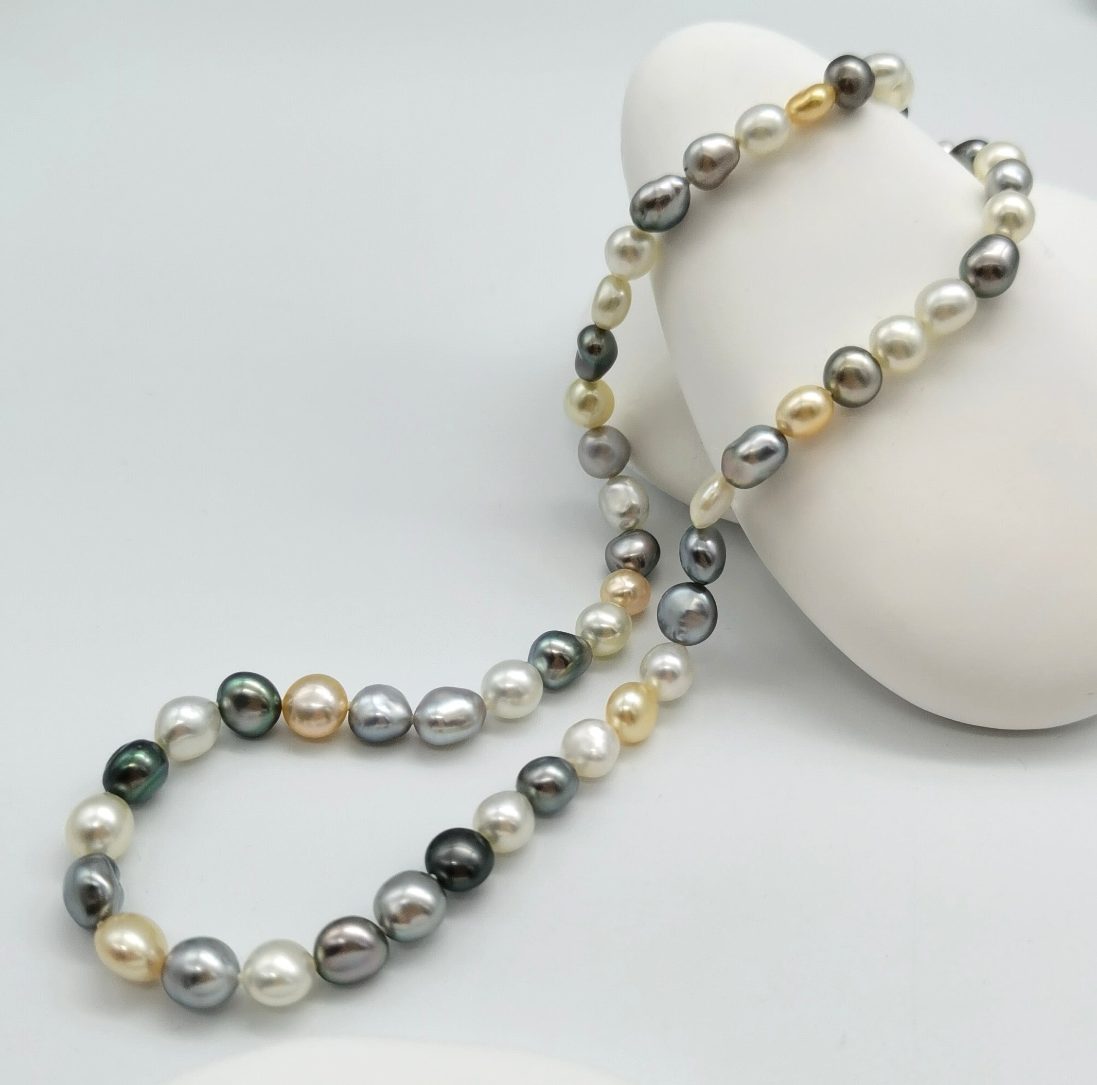 Close-up detail of tri-colour keshi pearl strand showing flat round Tahitian and South Sea pearls in natural colours
