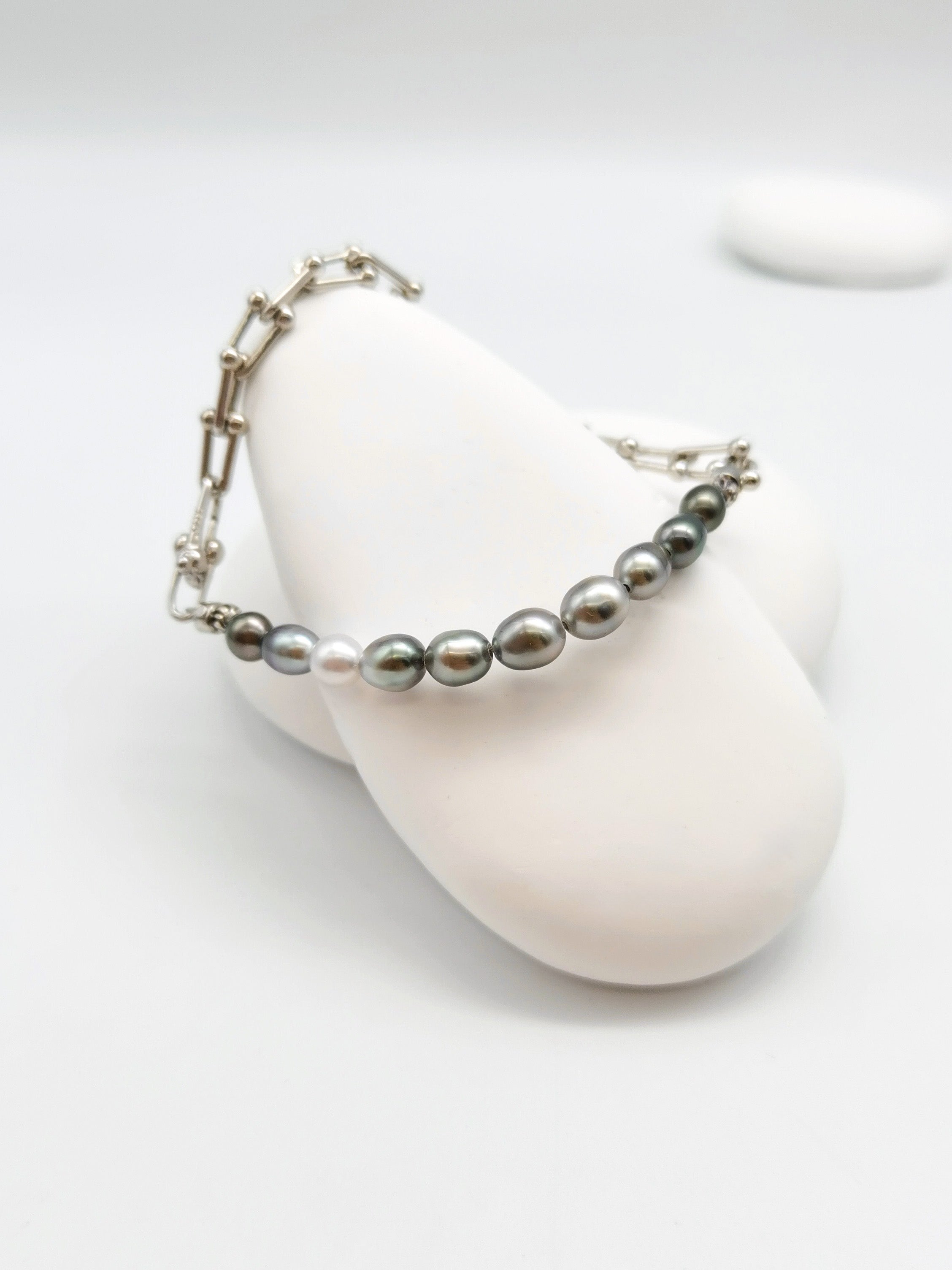 Close-up of 5.5mm oval Tahitian keshi pearls showing green iridescent lustre with white South Sea pearl on sterling silver chain