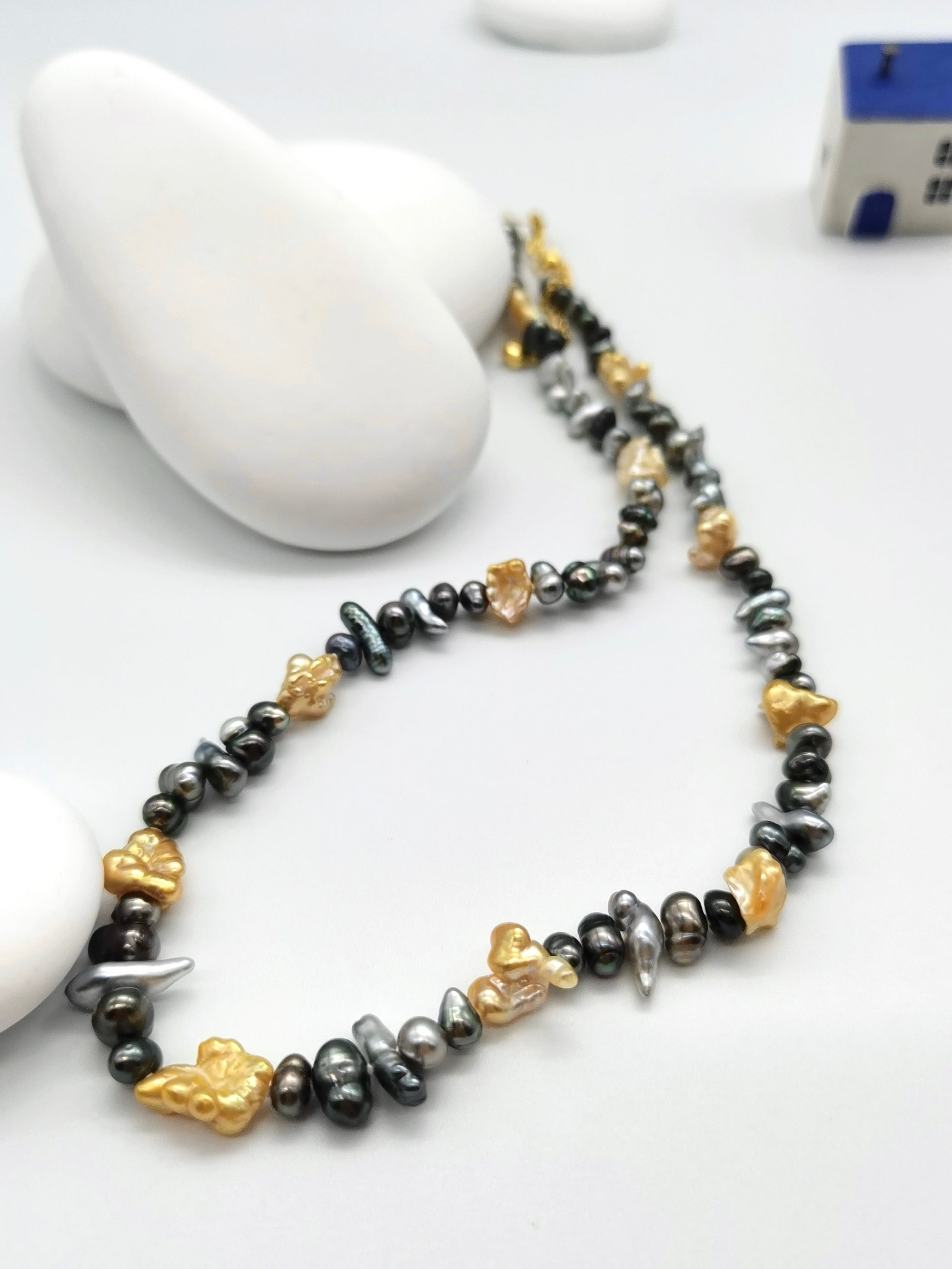 Full length view of 40cm Tahitian keshi pearl strand with gold South Sea pearl spacers displaying natural colour variations