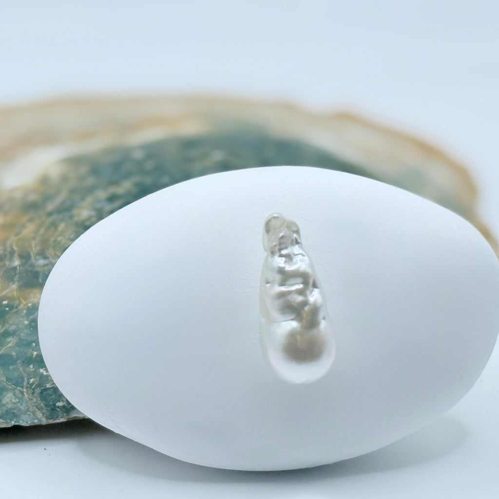 Pearl rest on a white stone with a natural oyster shell background