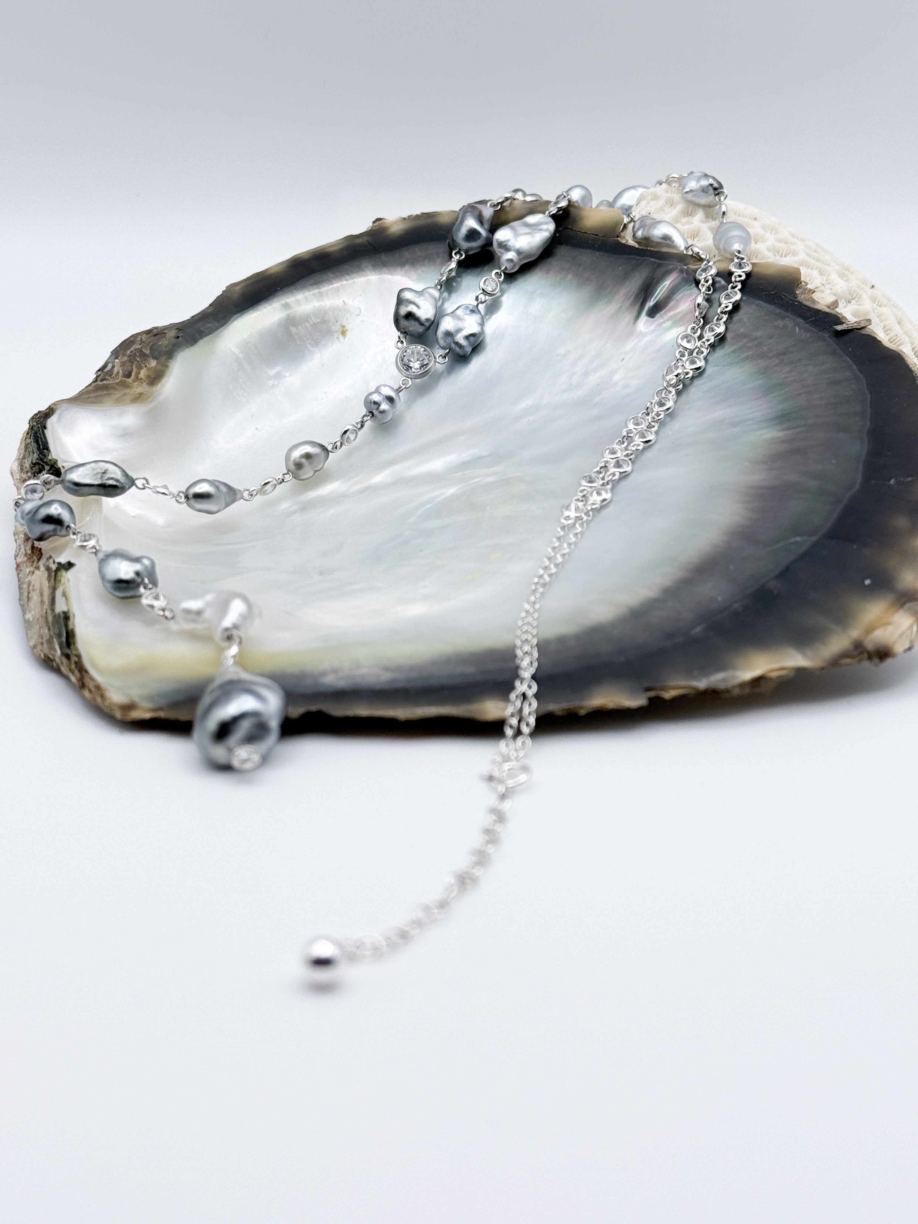 Side angle highlighting station-style silver chain and spectacle-set CZ links between pearls