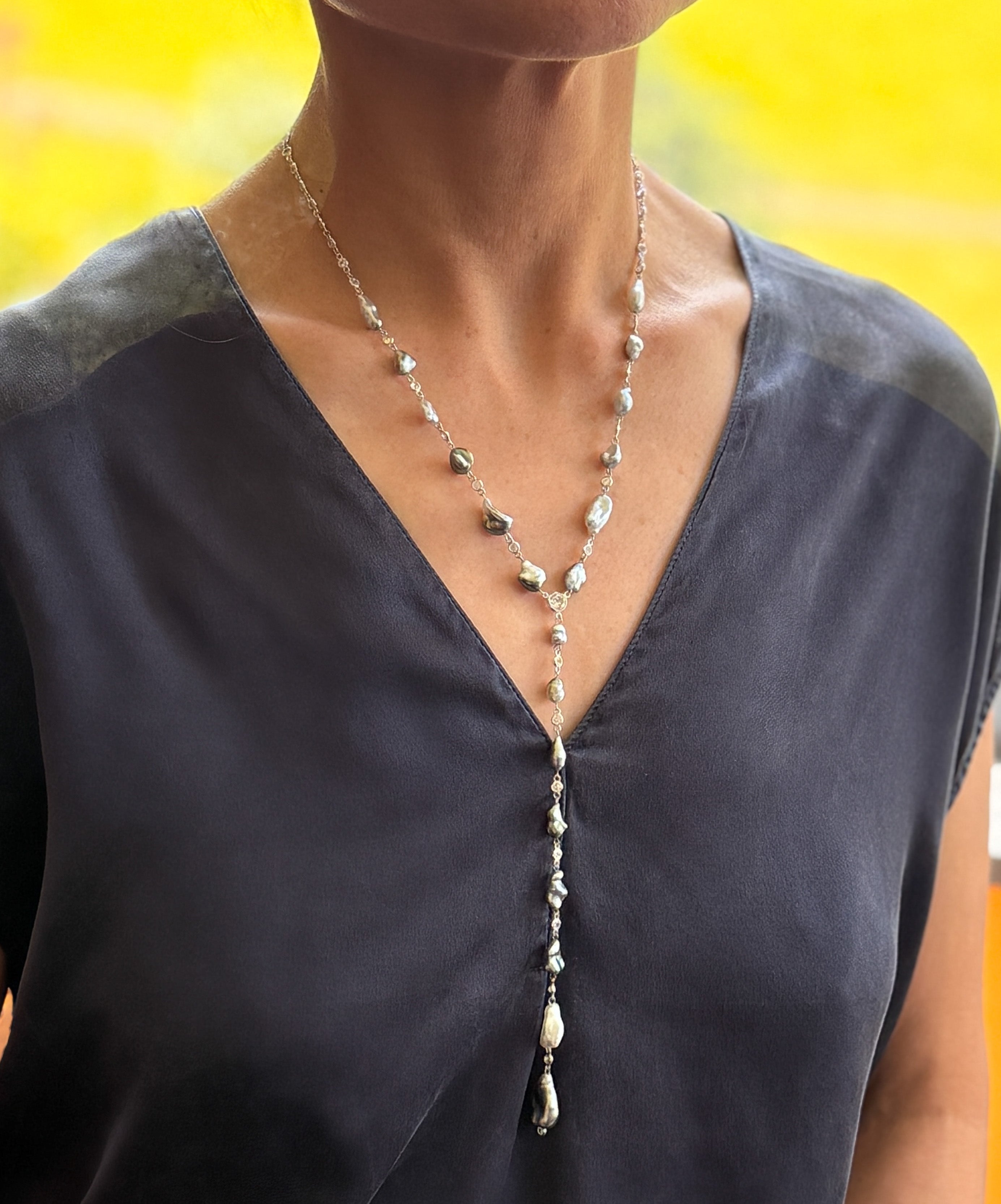 Model wearing necklace with dramatic Y-drop falling against a dark top for contrast