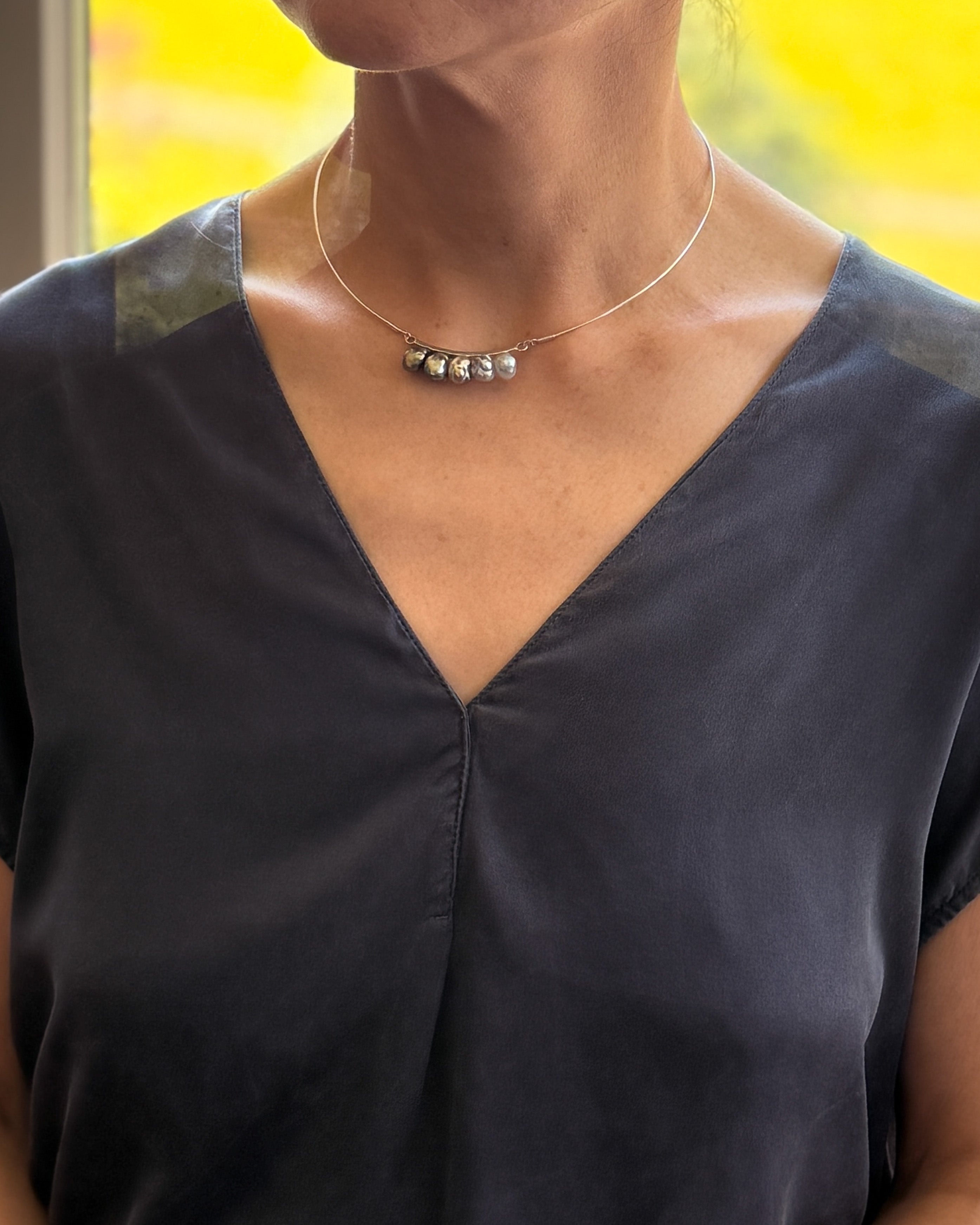 Model wearing necklace with pearls sitting along neckline on sculpted silver wire