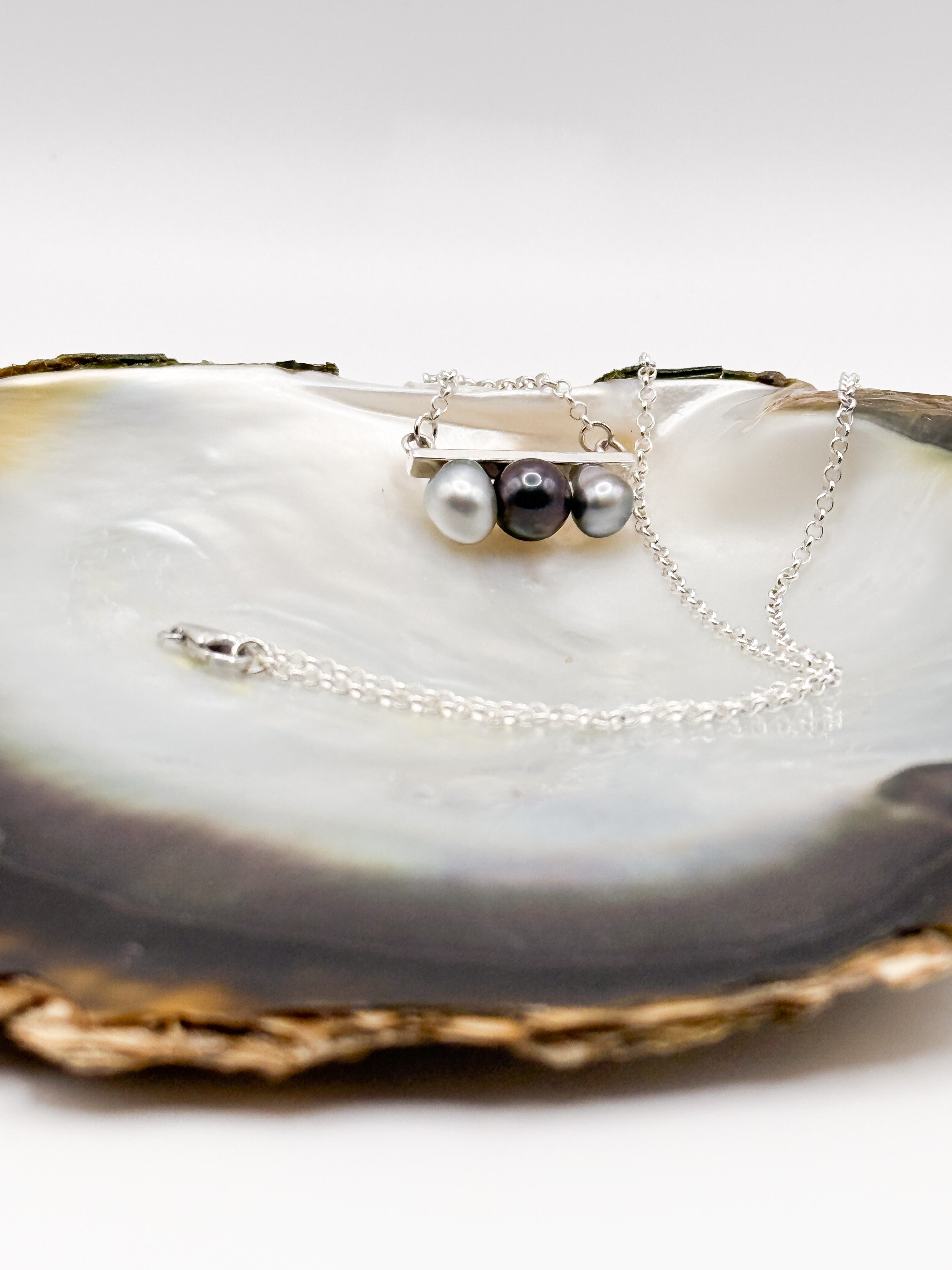 Close-up of three baroque pearls showing silver, green, and peacock overtones