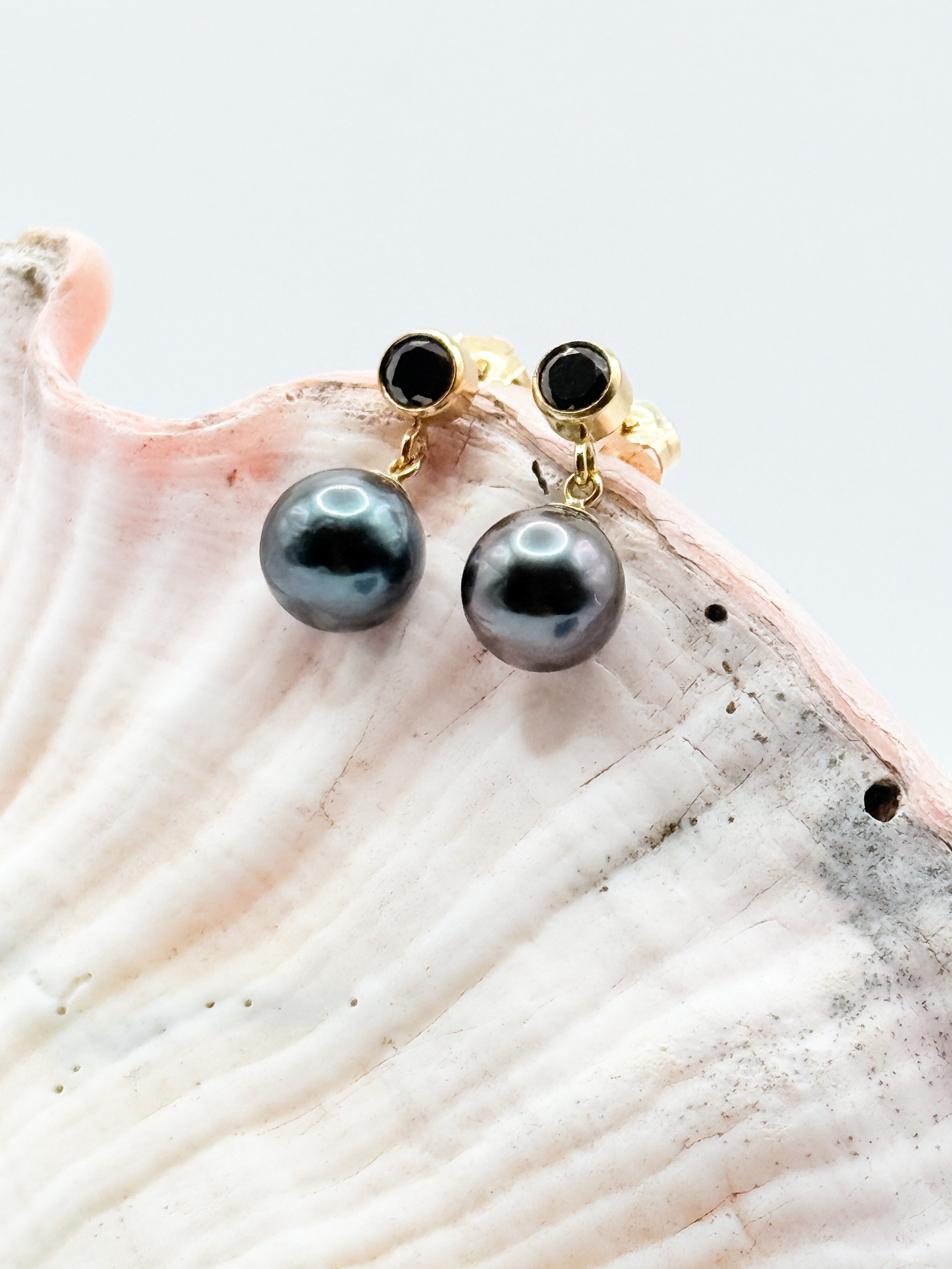 Front-facing view of pearl earrings with pink ceramic background highlighting lustre and contrast