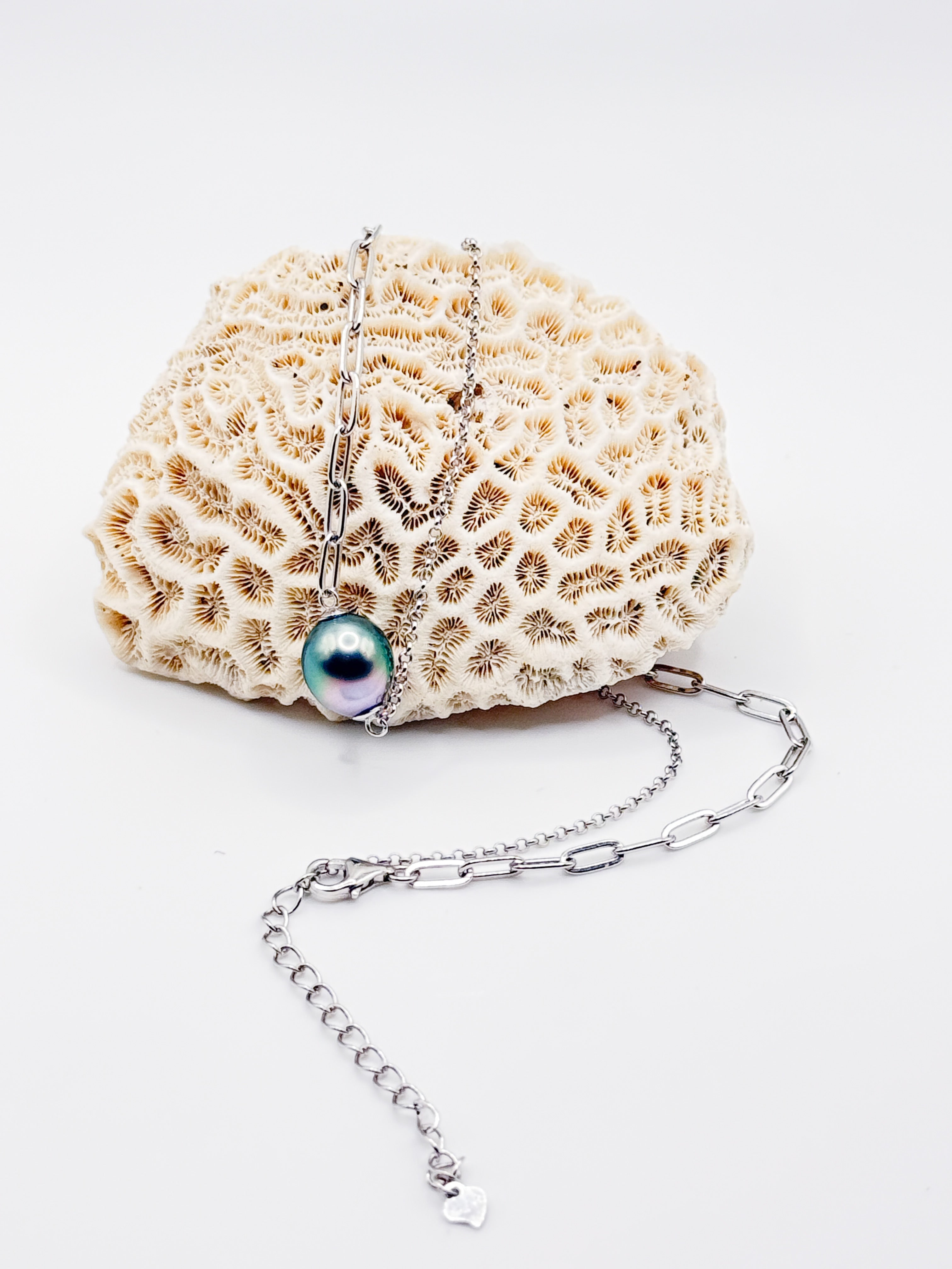 Tahitian baroque pearl necklace with mixed silver chains displayed on textured coral background