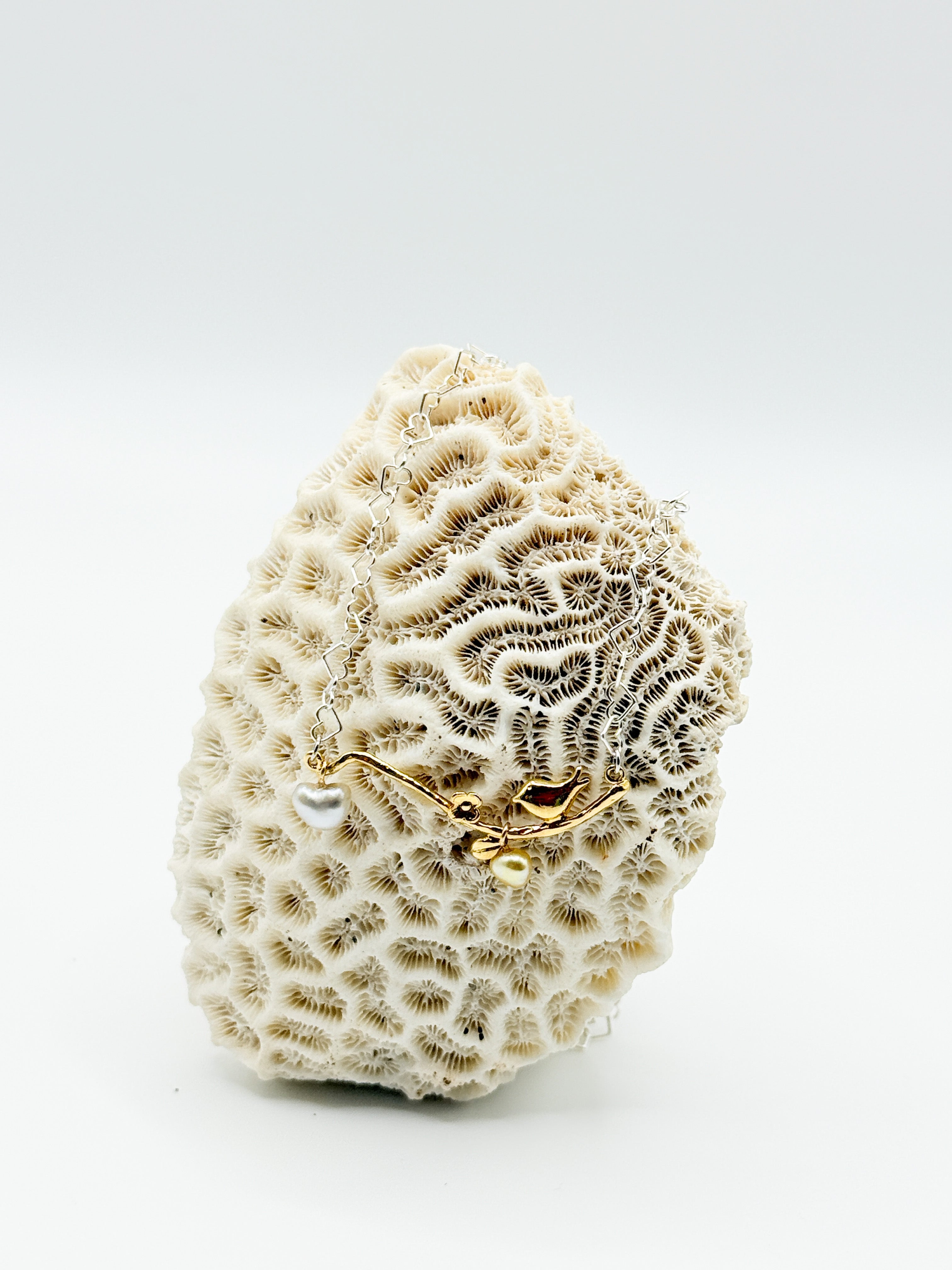 Front-facing image of pendant and chain arranged on coral background for texture contrast