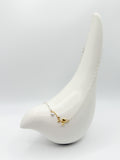Close-up of necklace on ceramic bird showing sculpted gold branch with white and golden heart pearls