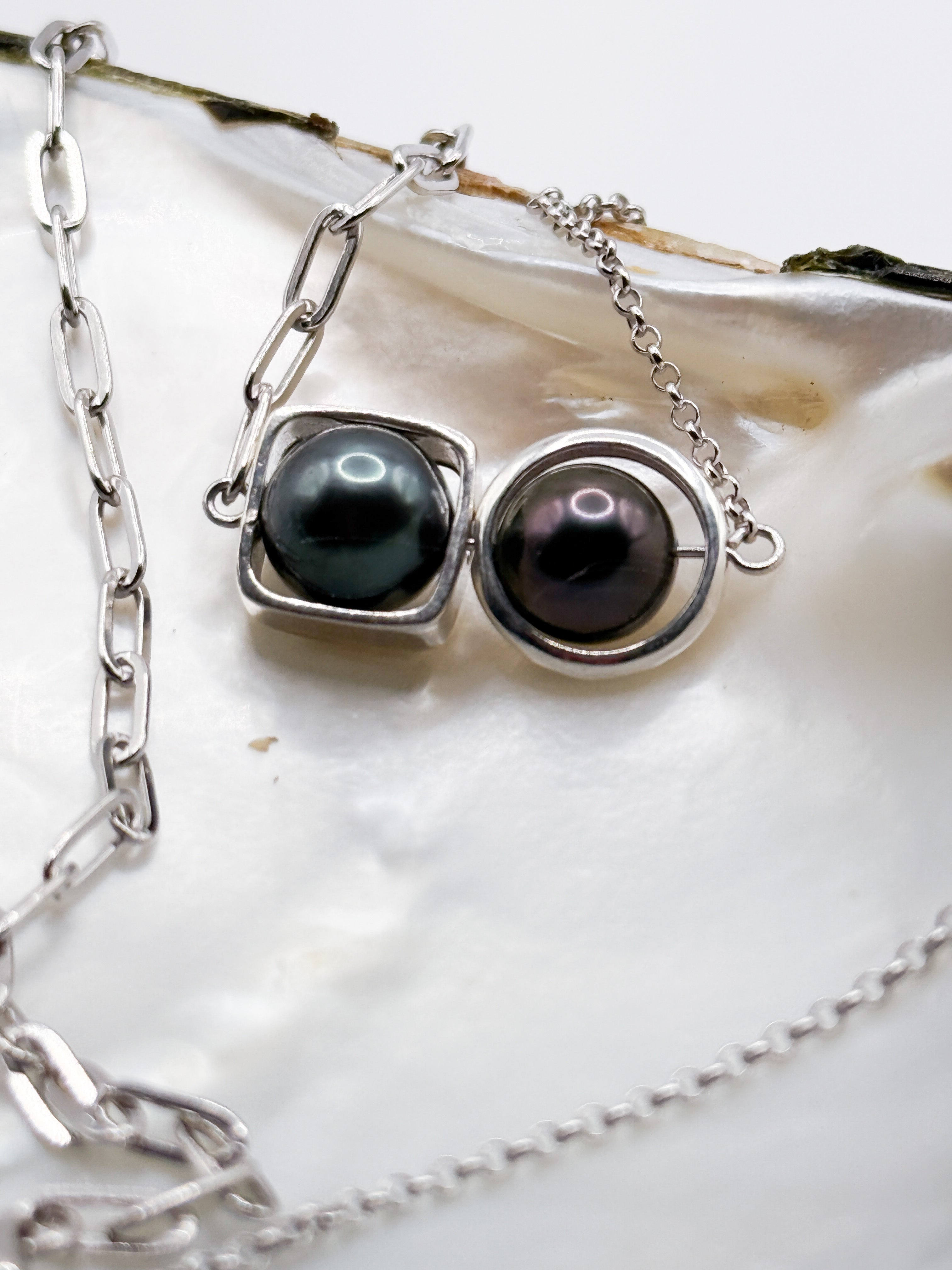 Close-up of dark Tahitian pearls with high lustre in round and square silver bezel settings
