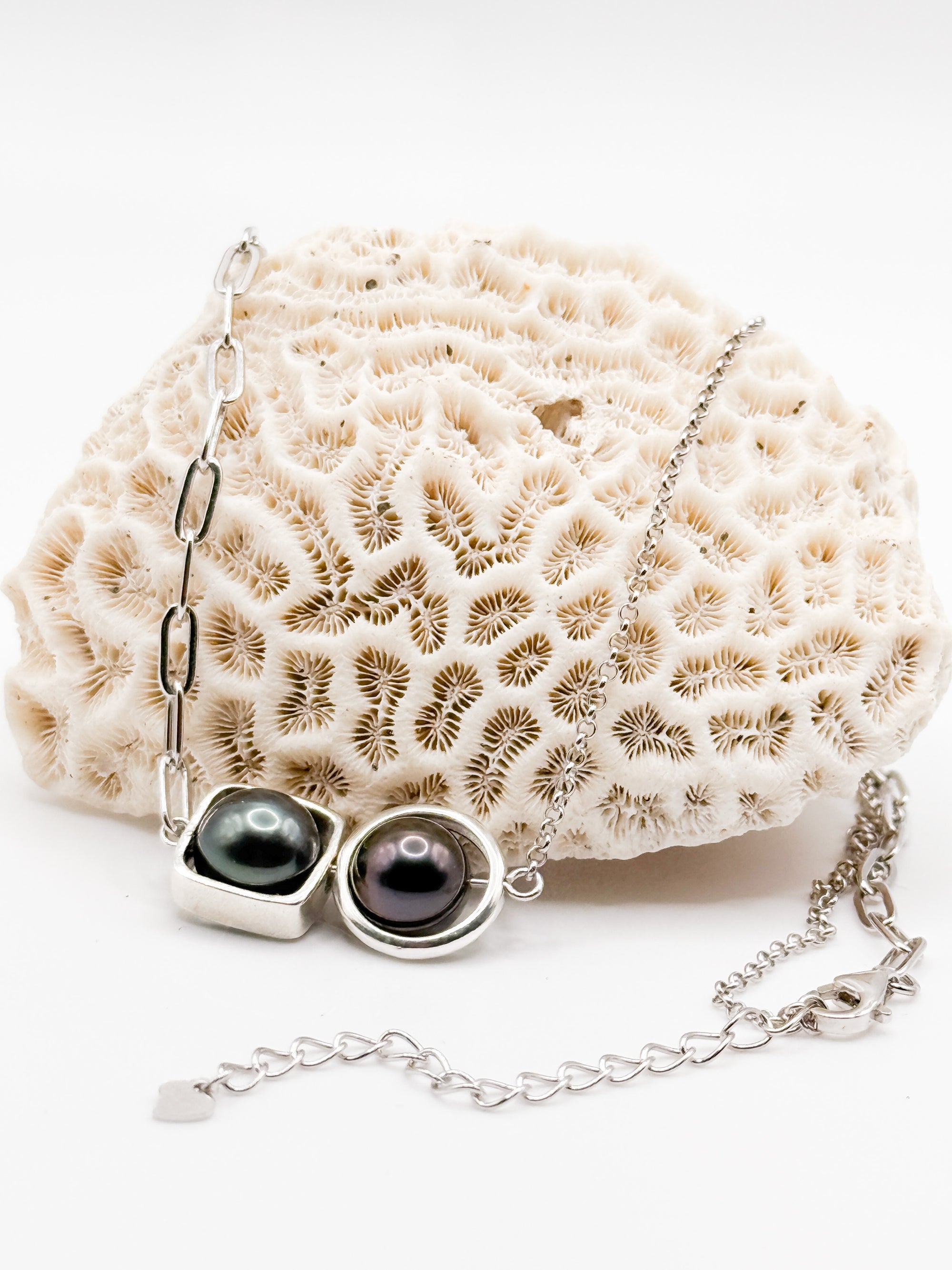 Front view of necklace arranged on coral-textured prop, showing chain variation and clasp detail