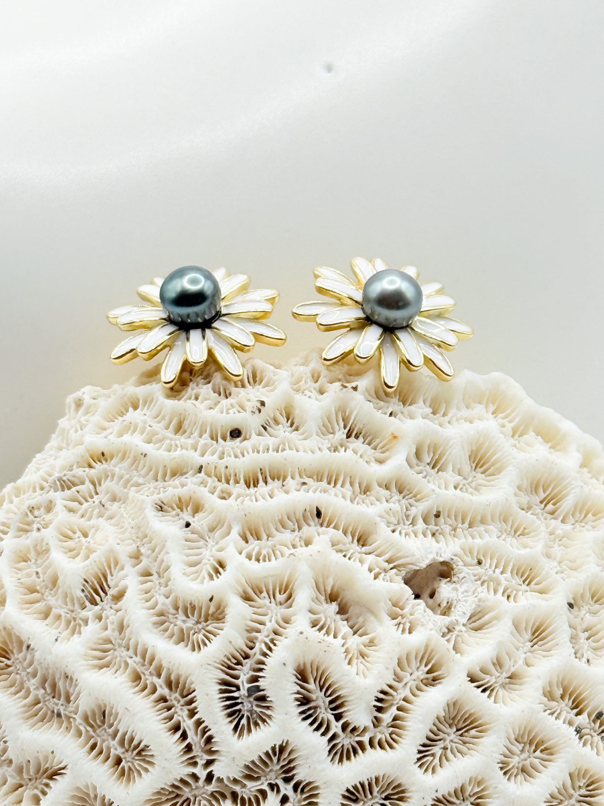 Close-up showing enamel daisy petals with iridescent Tahitian pearls at centre of gold-plated studs