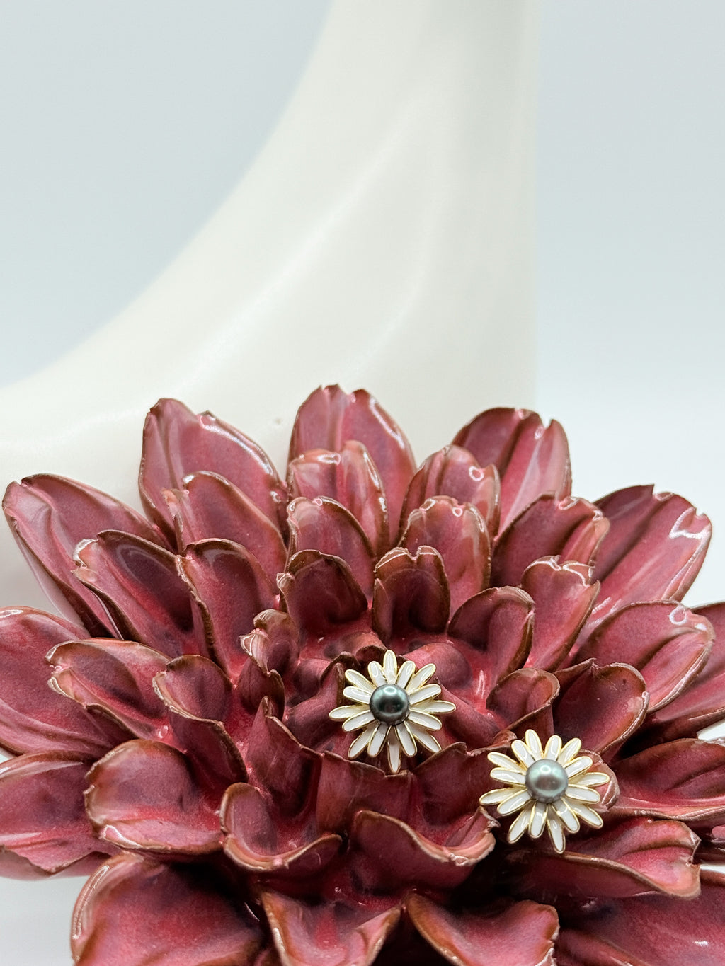 Closed-up image of earrings nestled in red flower to show dimension and size against organic shapes