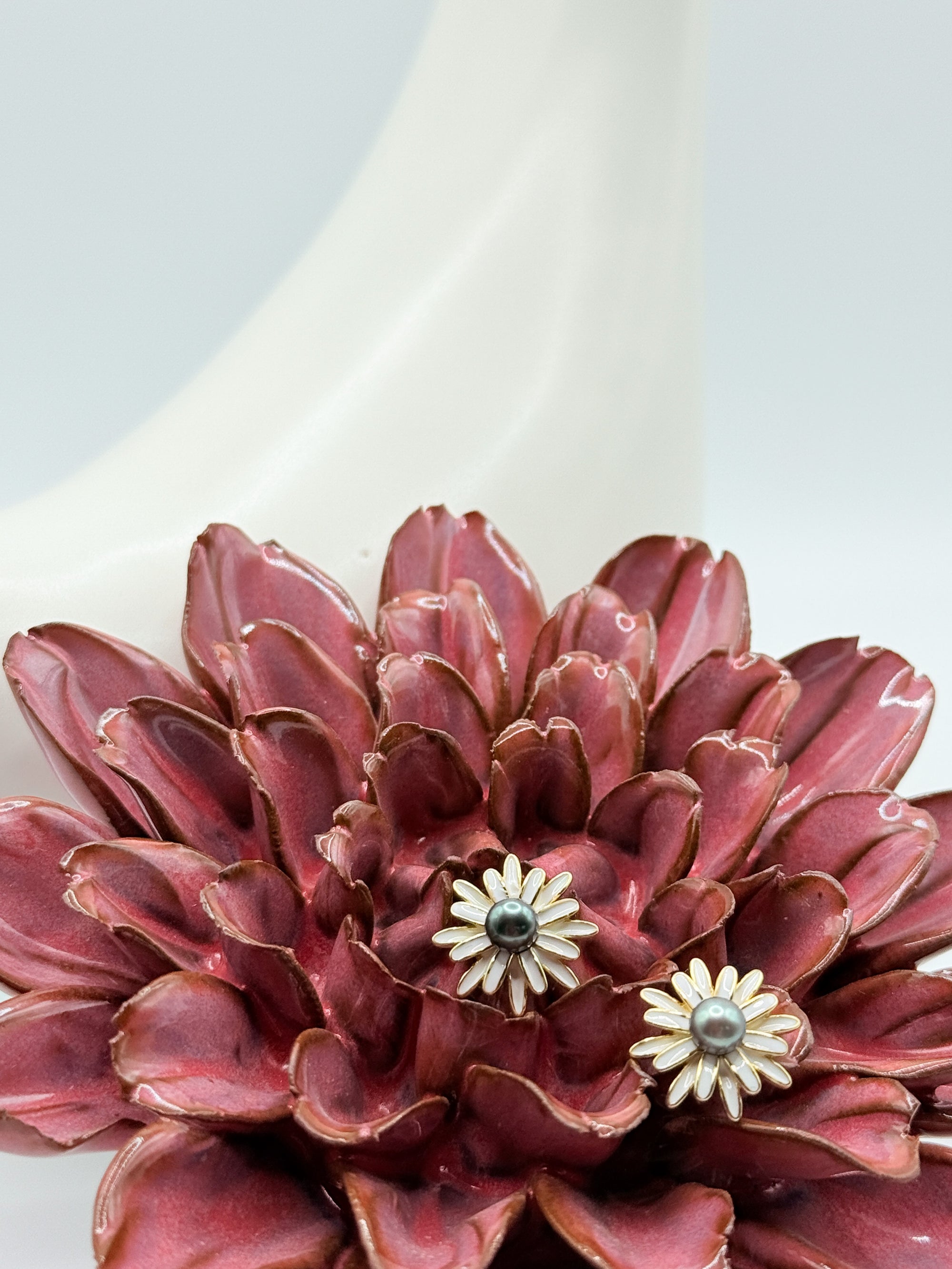 Closed-up image of earrings nestled in red flower to show dimension and size against organic shapes