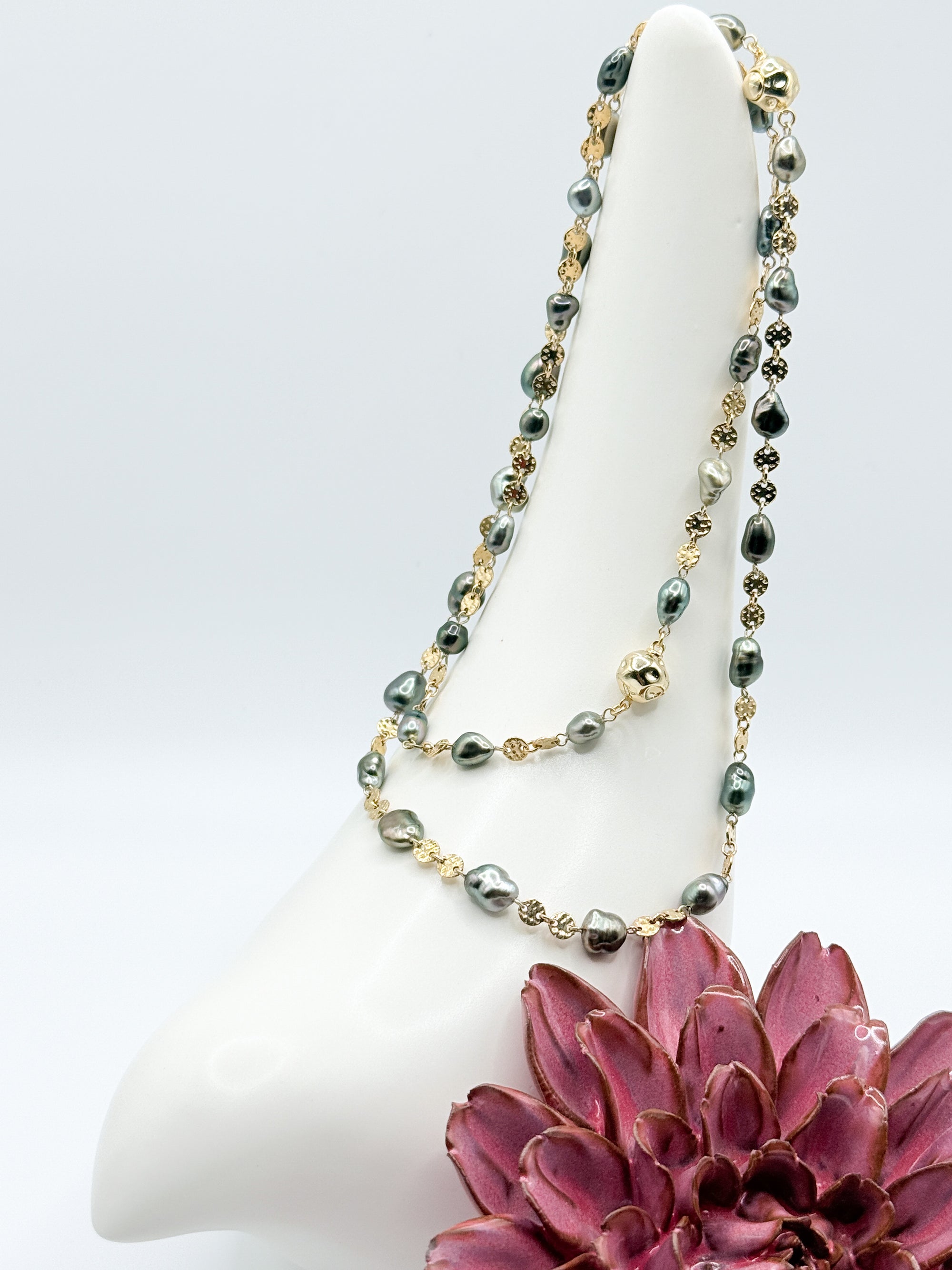 Necklace coiled on ceramic bird prop showing alternating gold-filled links and baroque pearls
