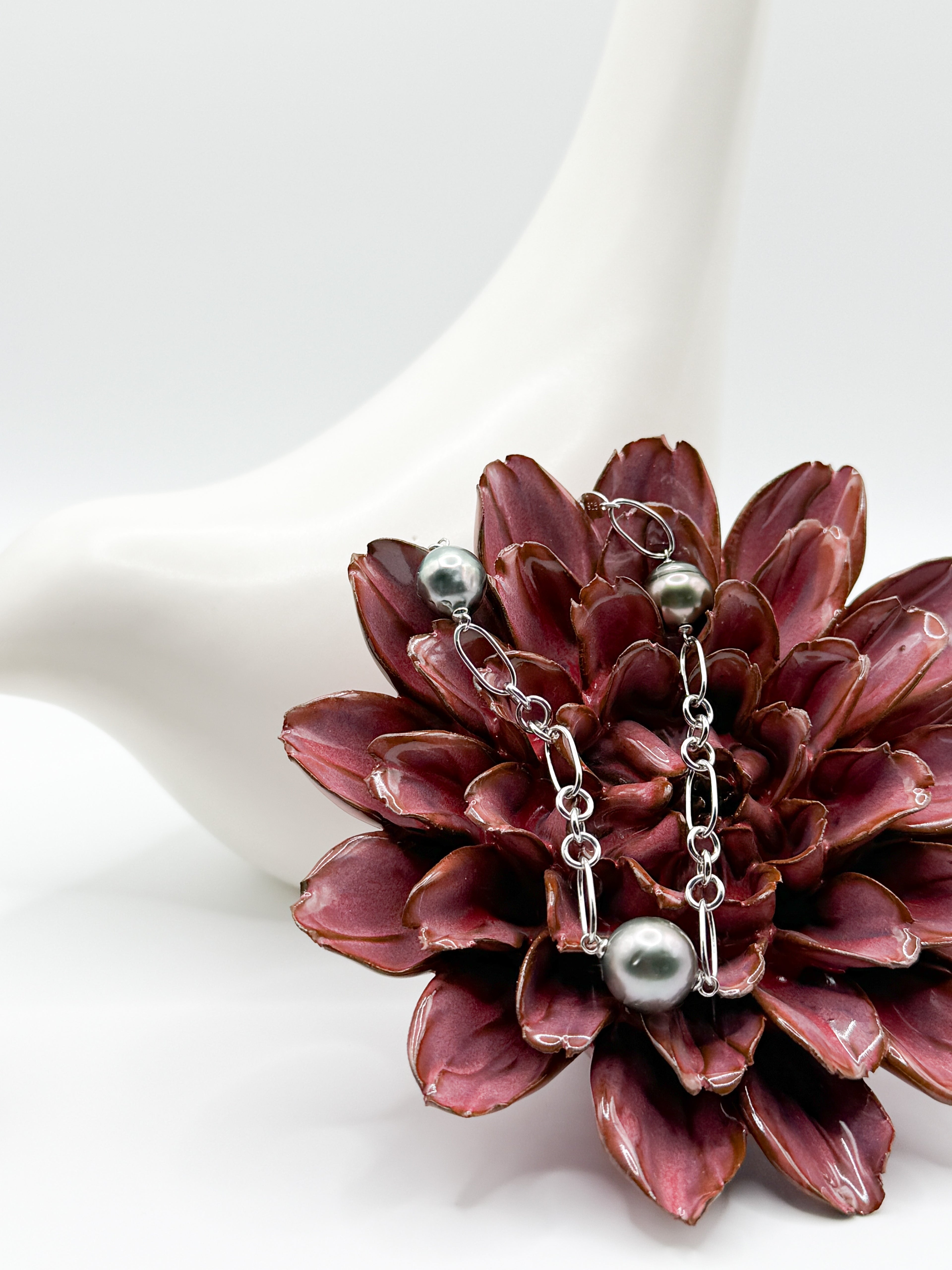 Tahitian baroque pearl bracelet with three pearls on sterling silver Figaro chain, styled on red flower and ceramic bird.