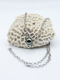 Floating Tahitian pearl pendant necklace displayed on coral, showing polished sterling silver chain and clasp.