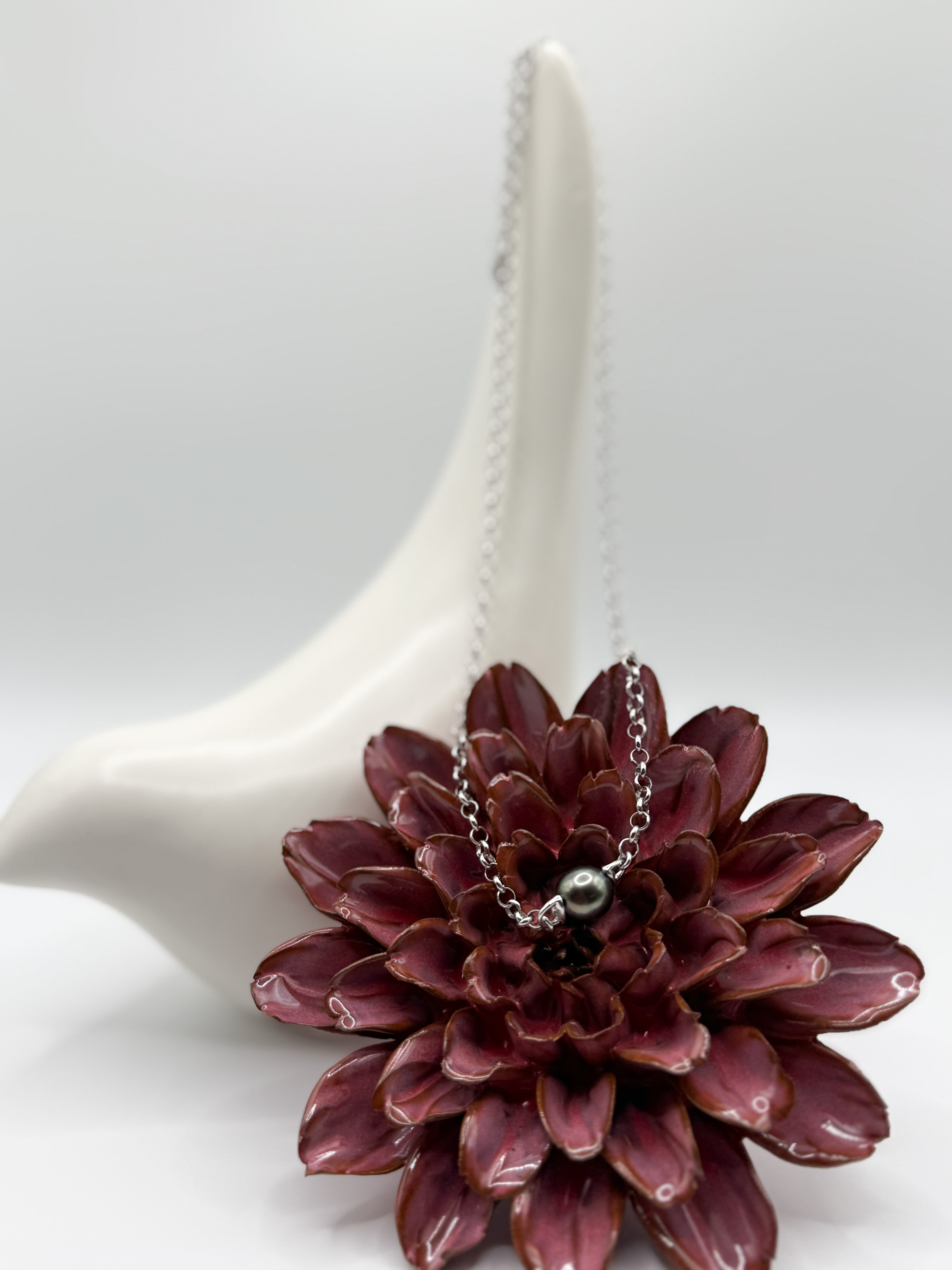 Tahitian baroque pearl pendant necklace on 925 silver chain, draped over red flower and ceramic bird.