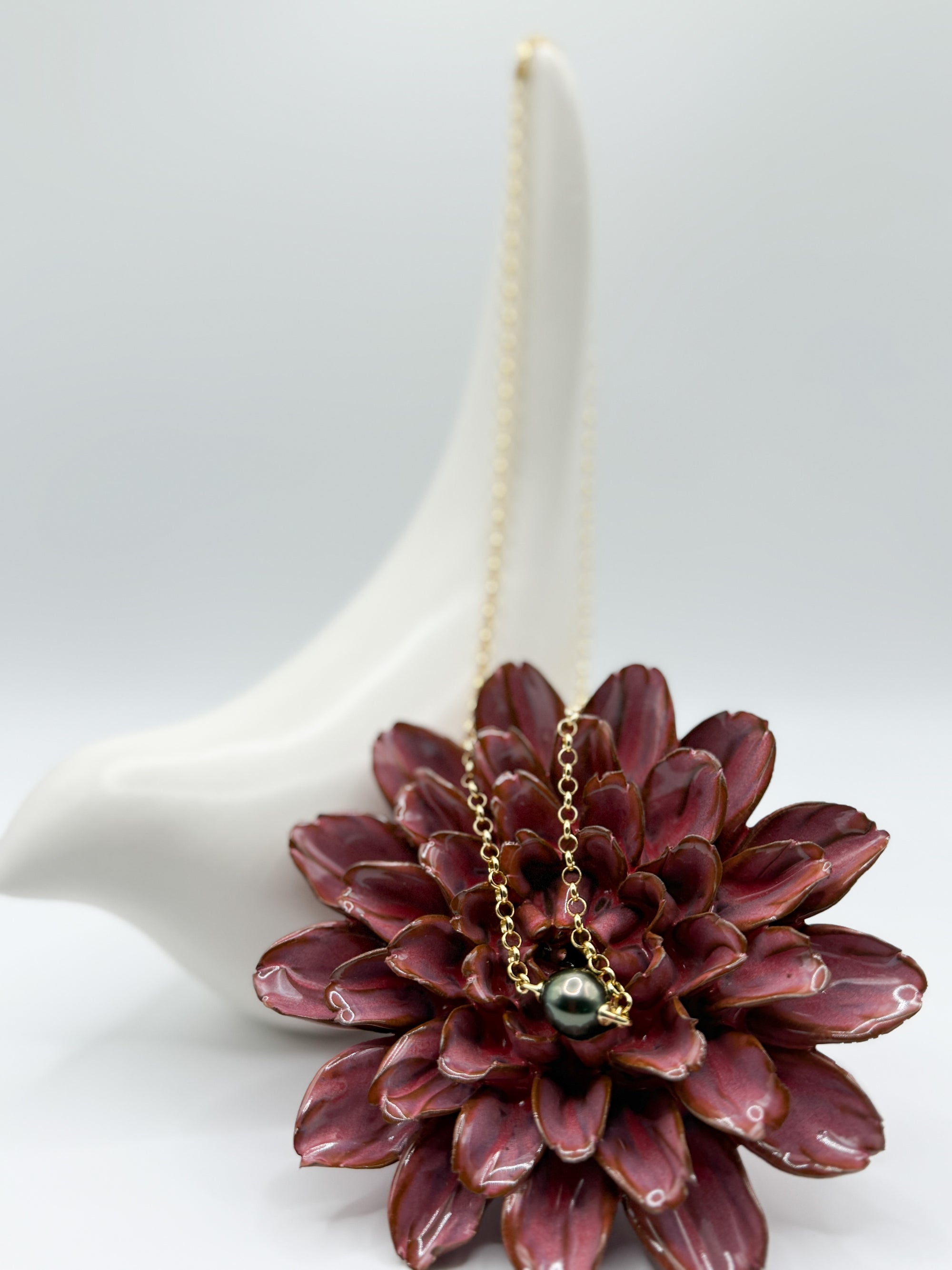 Tahitian baroque pearl pendant necklace on 925 silver chain, draped over red flower and ceramic bird.
