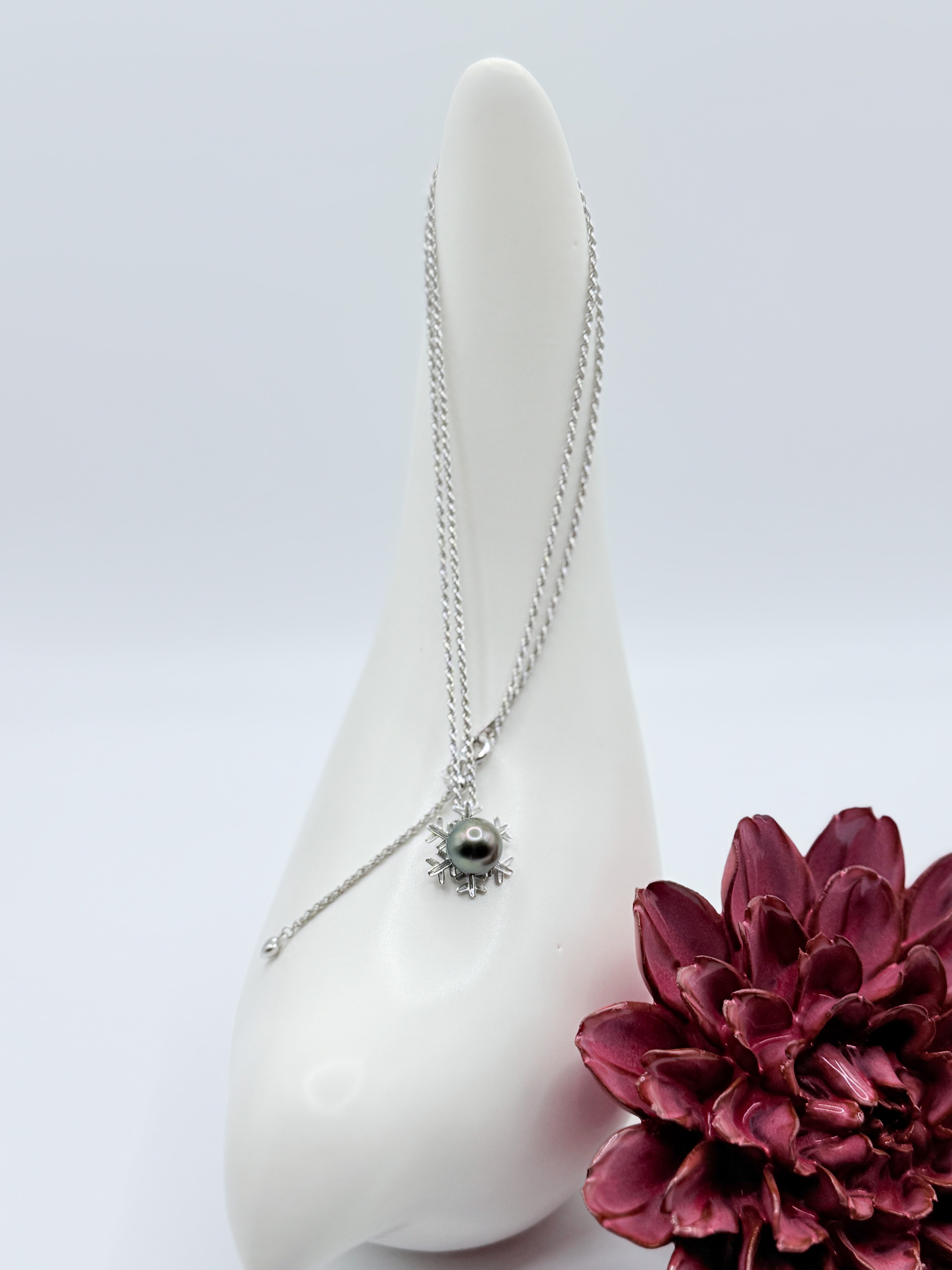 Full necklace view showing the sterling silver rope chain and snowflake pendant with central Tahitian pearl.
