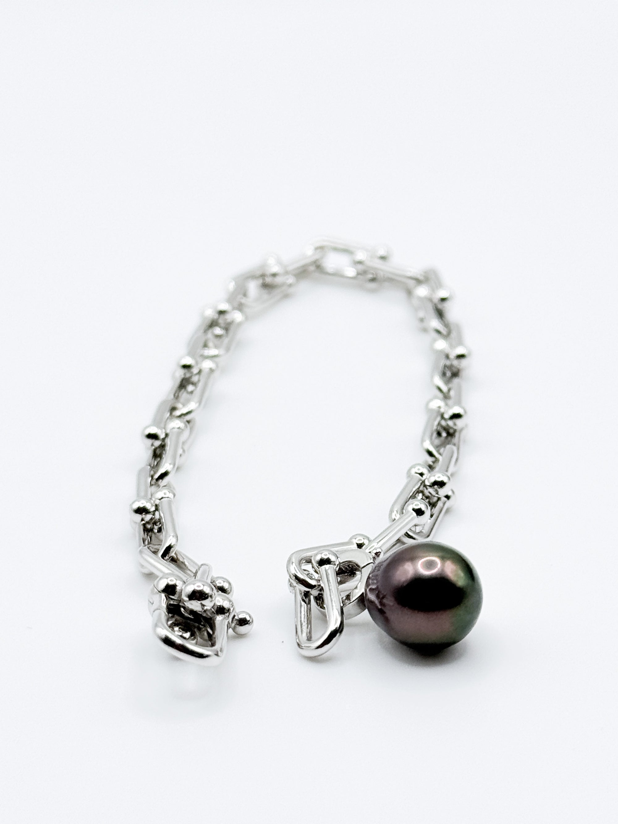 Sterling silver chain bracelet with dark Tahitian baroque pearl charm displayed on white background