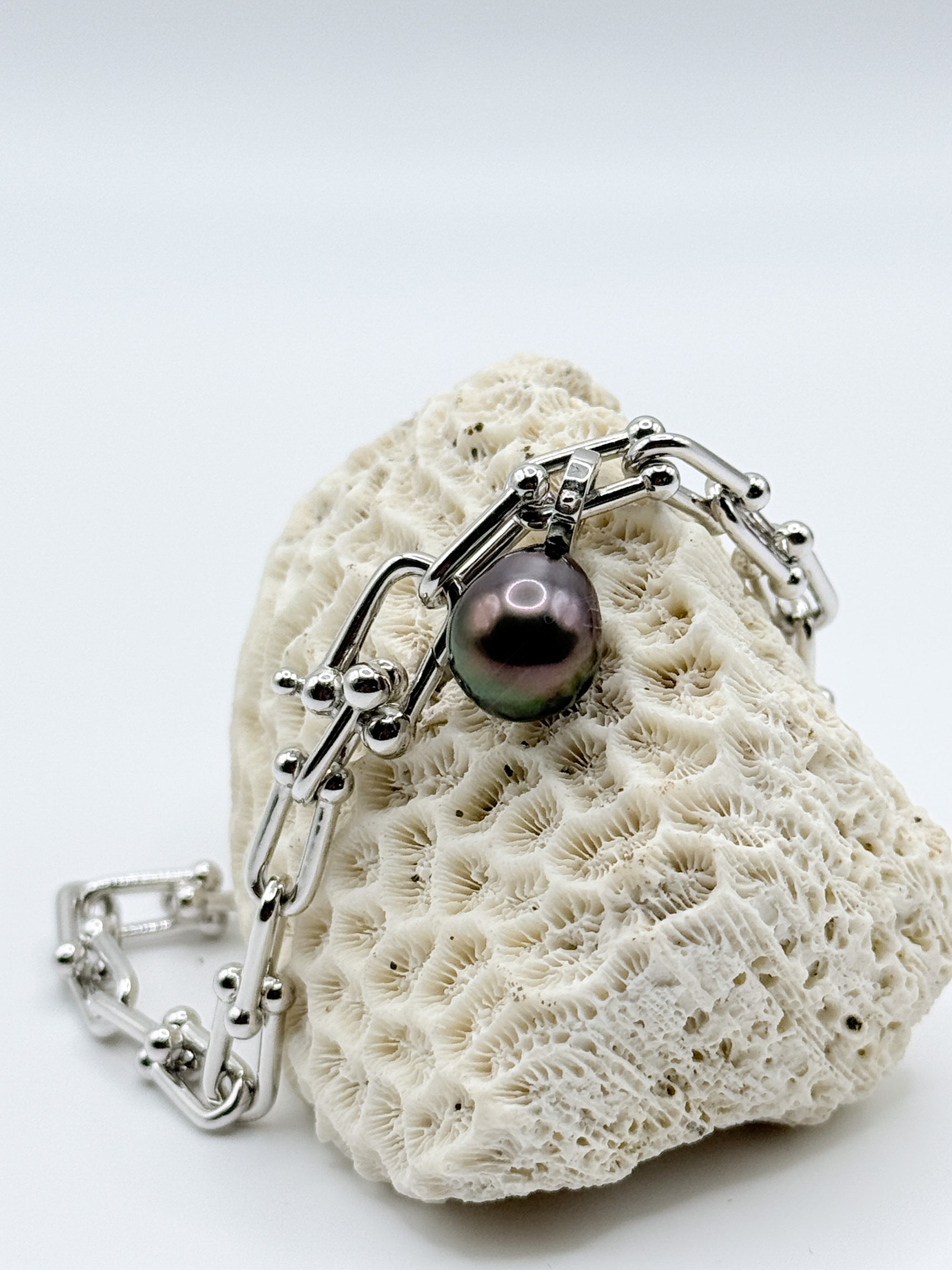 Sterling silver chain bracelet with Tahitian pearl charm artistically arranged on white coral, showing the bracelet's full length and chunky chain design