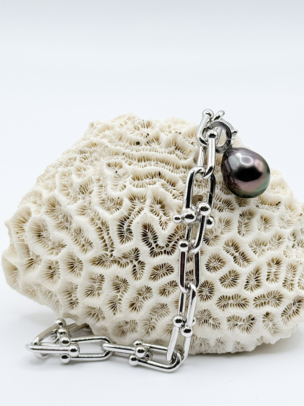 Sterling silver chain bracelet with Tahitian pearl charm displayed on white coral showing detailed view of the clasp mechanism and chain construction