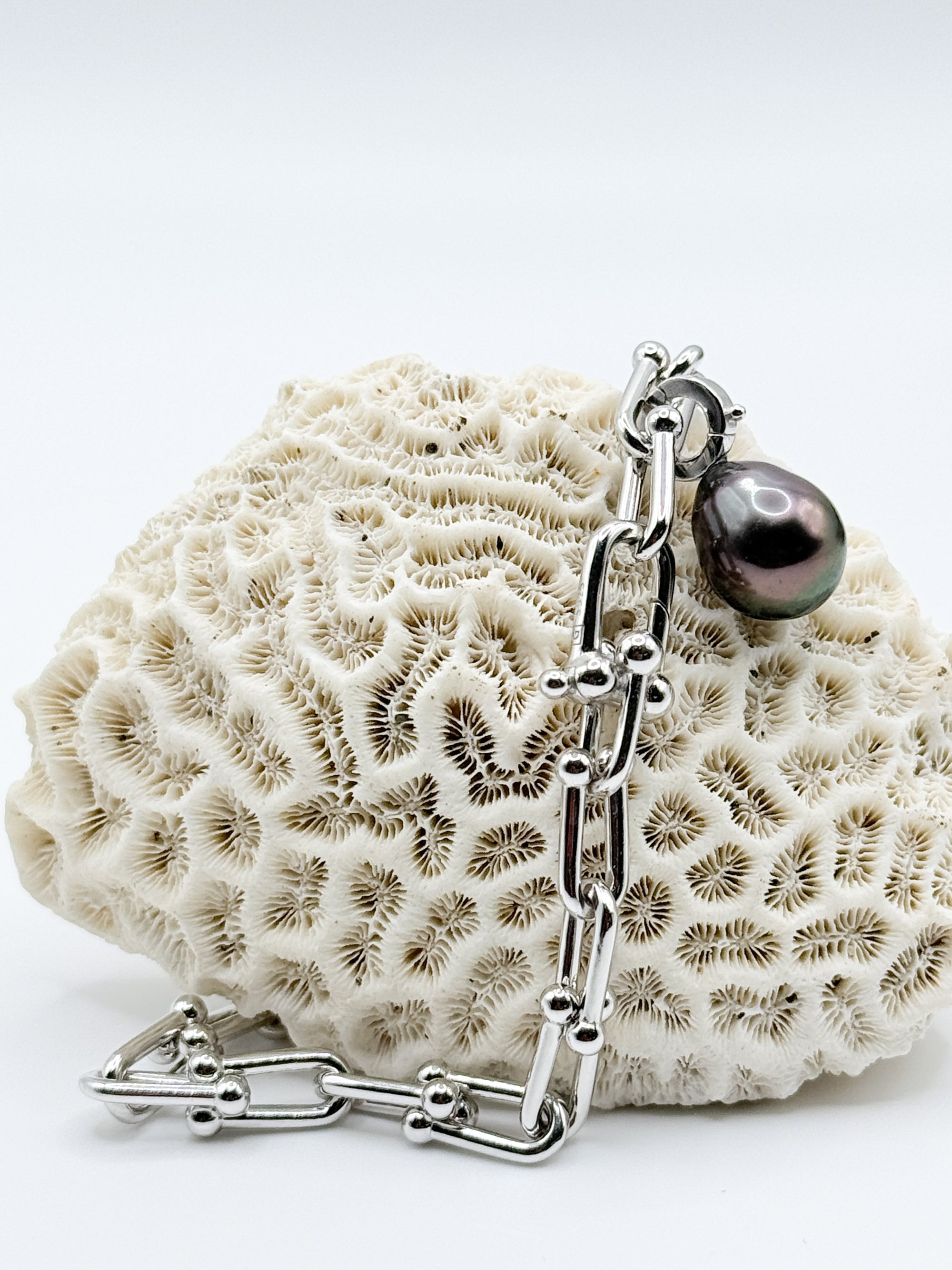 Sterling silver chain bracelet with Tahitian pearl charm displayed on white coral showing detailed view of the clasp mechanism and chain construction
