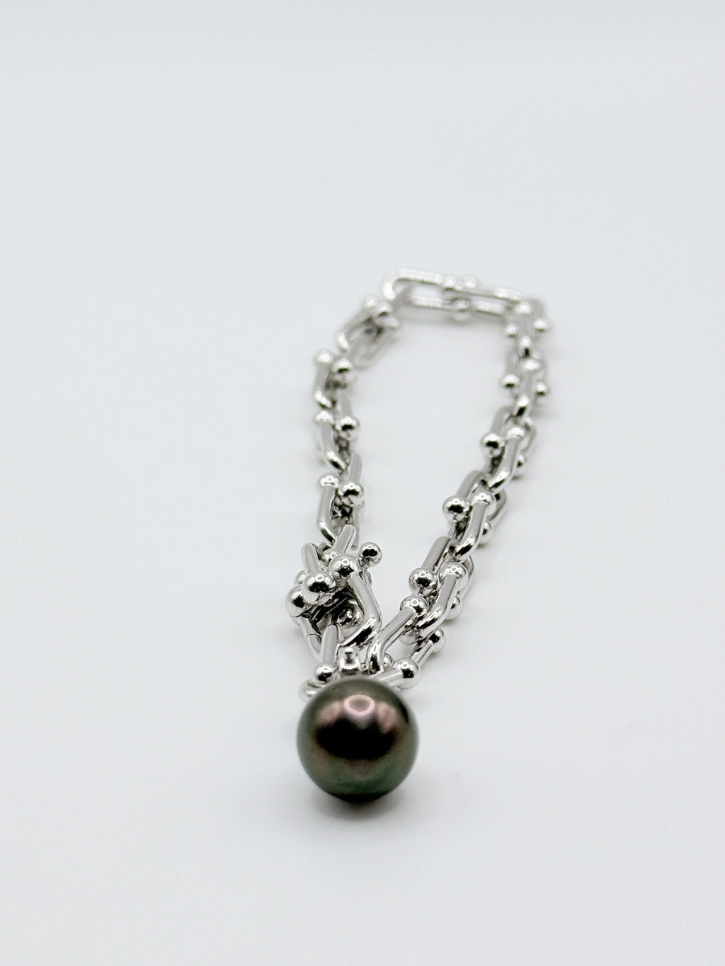 Close-up view of sterling silver chain bracelet showing detailed link pattern with dark Tahitian pearl charm pendant