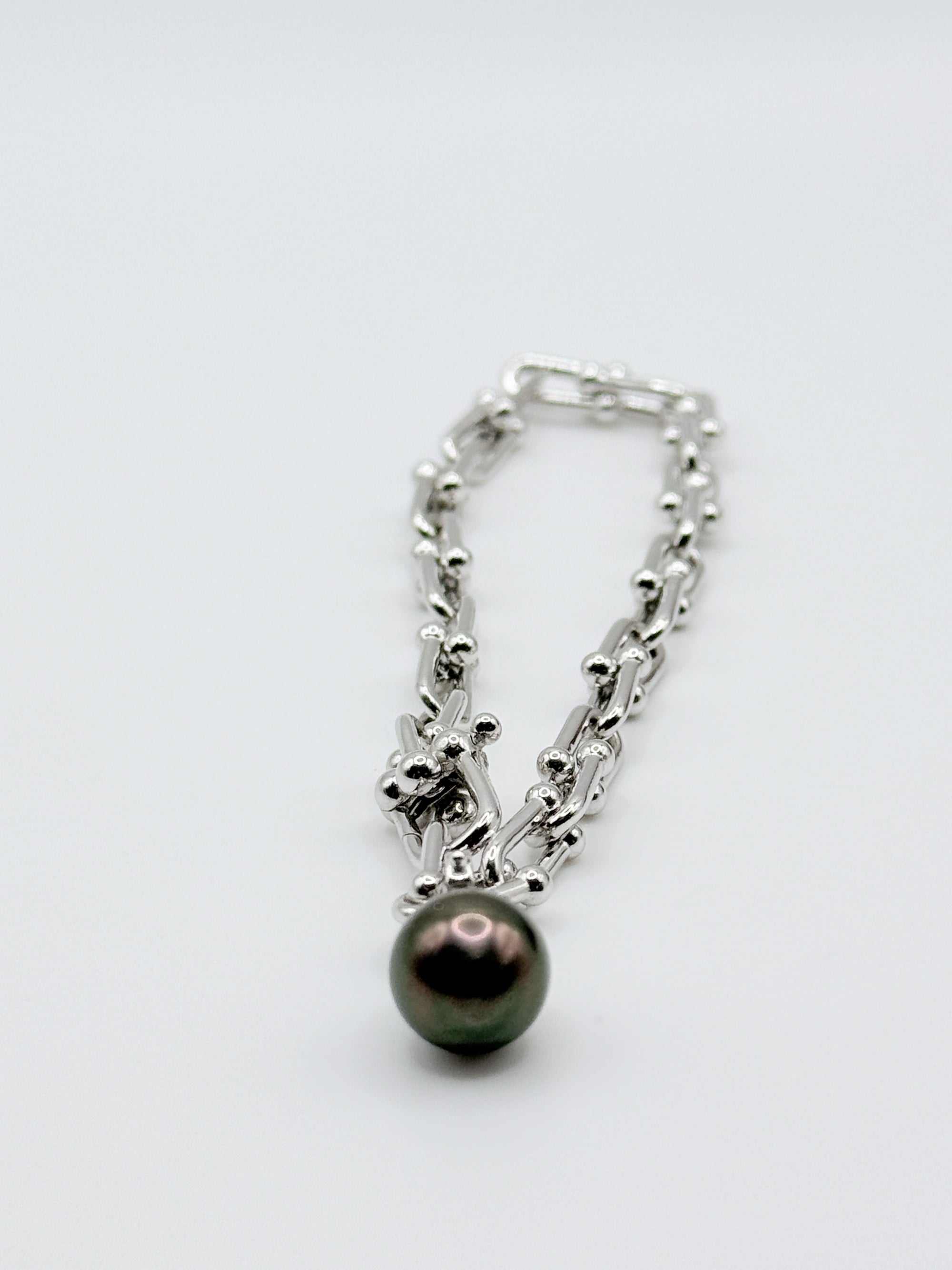 Close-up view of sterling silver chain bracelet showing detailed link pattern with dark Tahitian pearl charm pendant