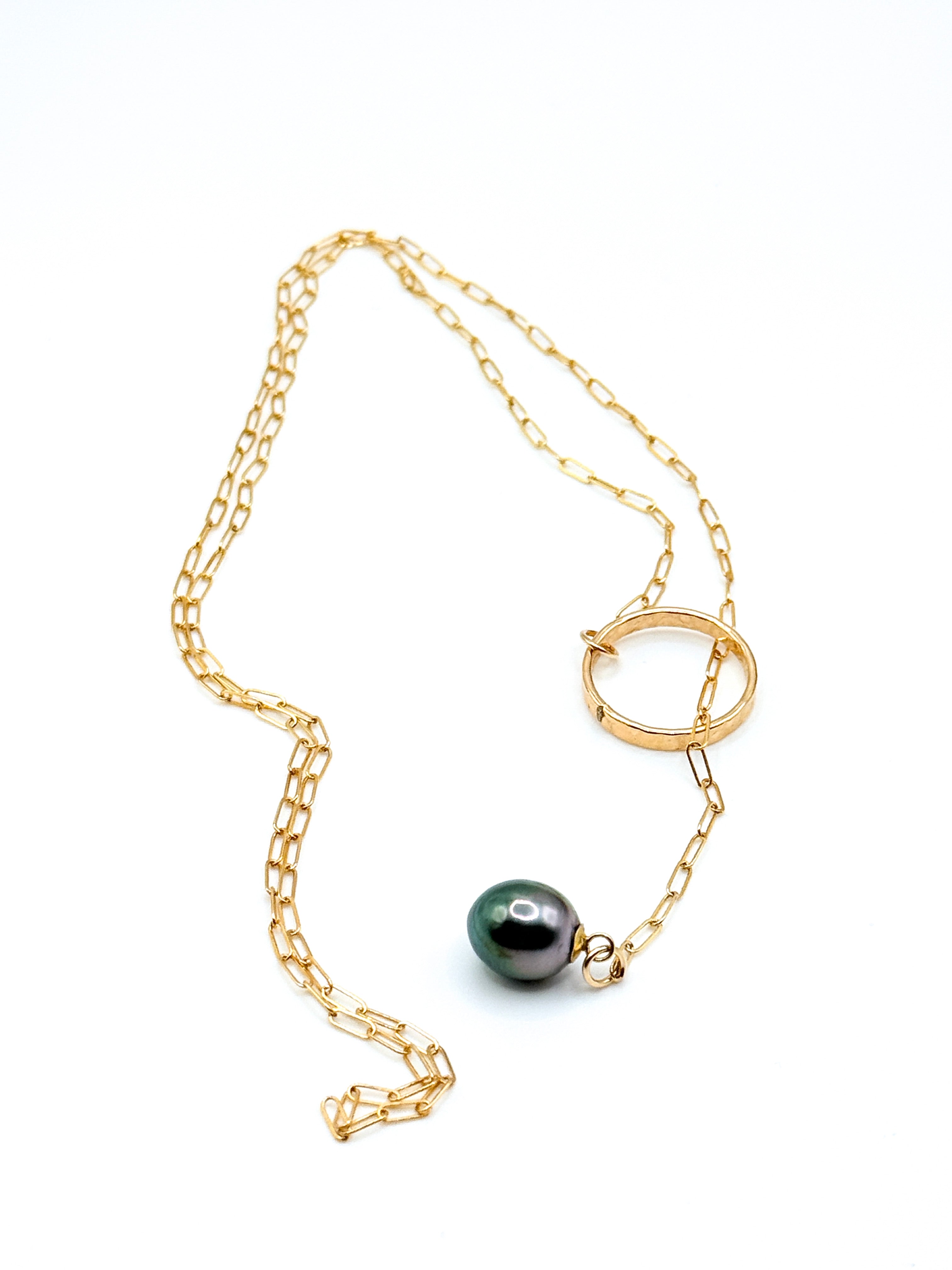 Gold chain lariat necklace with dark Tahitian pearl laid flat showing full length of chain, circular ring detail, and pearl pendant on white background