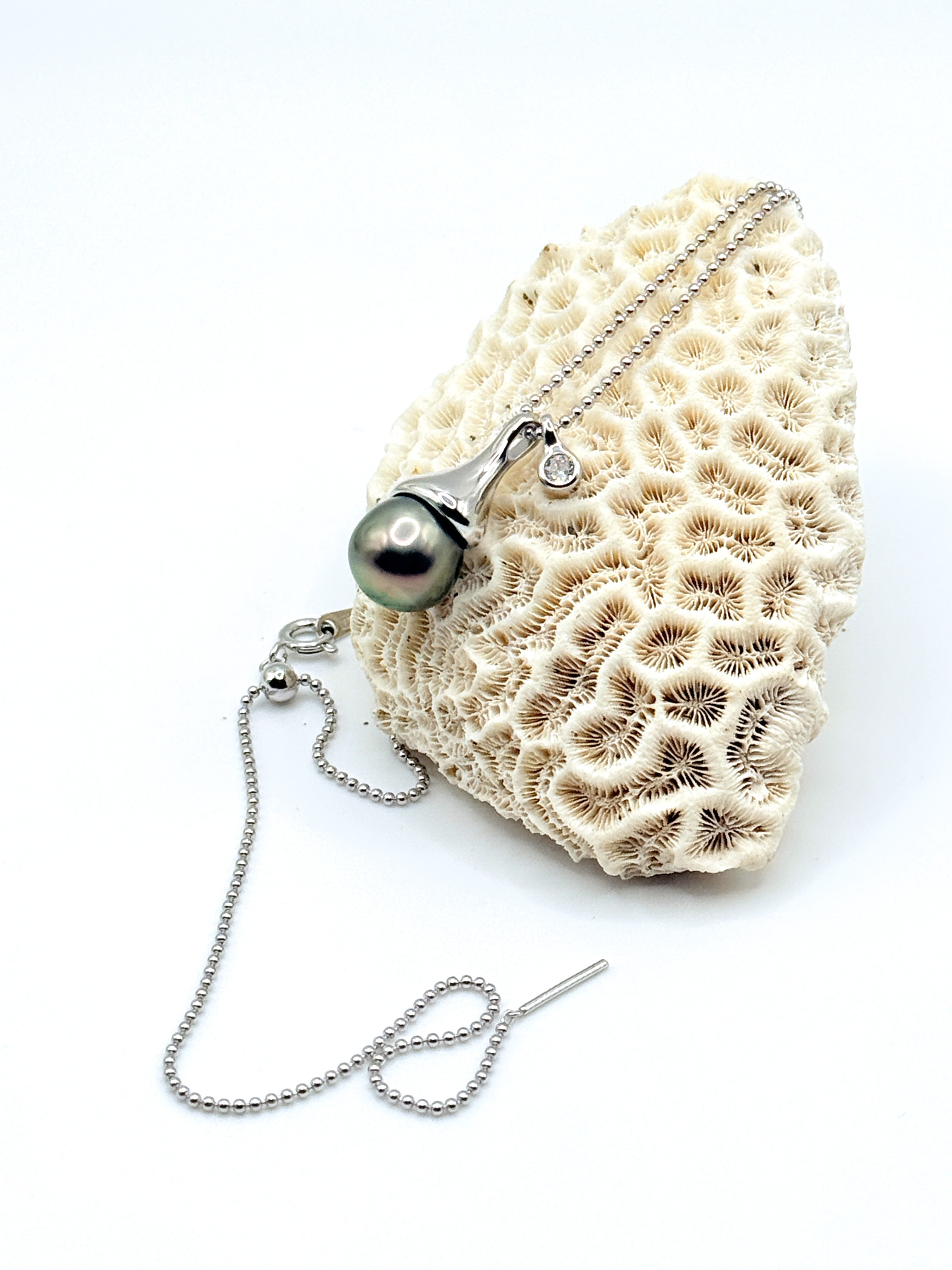Sterling silver ball chain necklace with Tahitian pearl pendant displayed on white coral specimen, showing full length of ball chain and modern pendant design