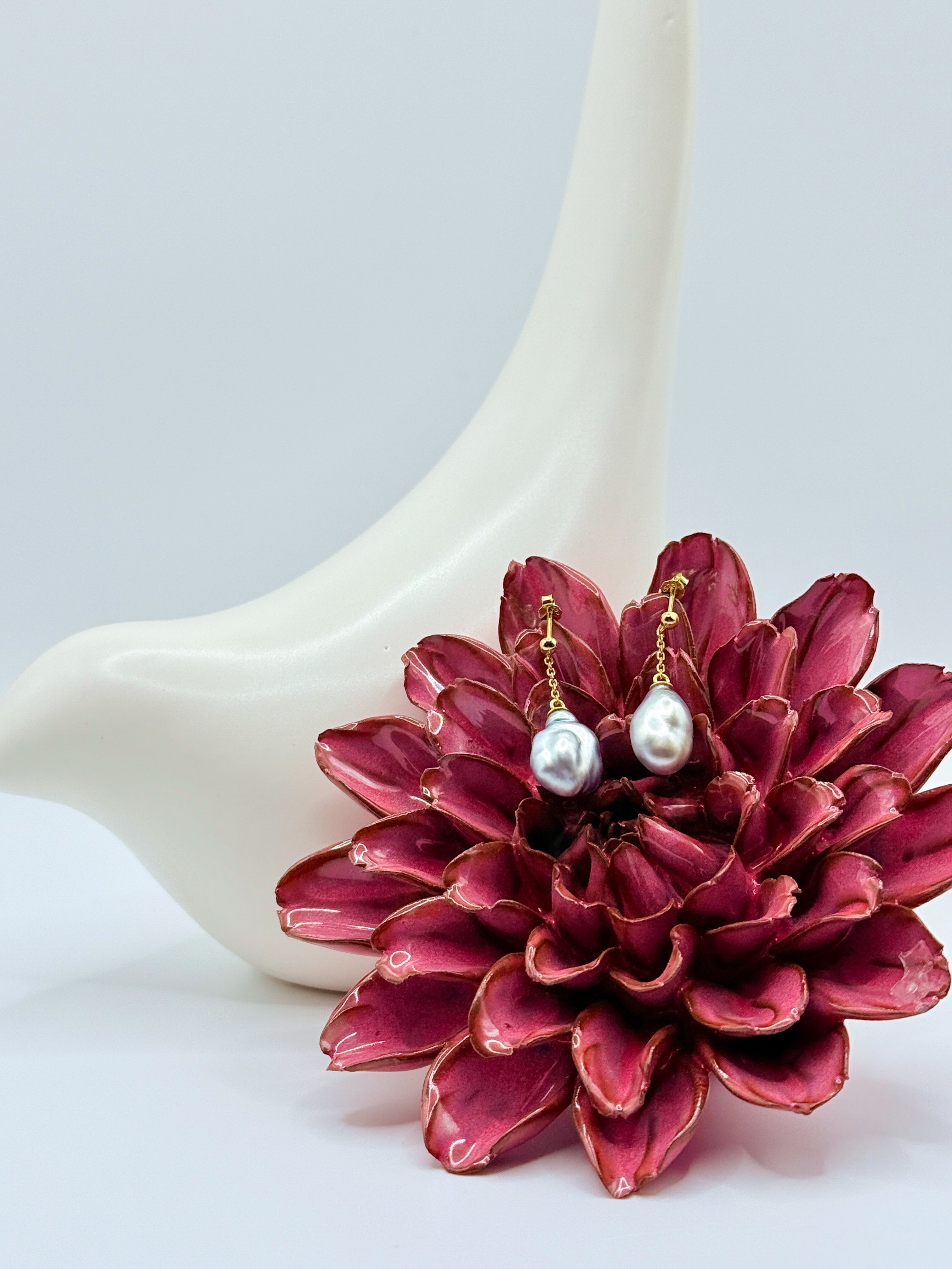 Gold drop earrings with silver-grey Tahitian keshi pearls on delicate chain, styled with burgundy succulent flower and white ceramic vase